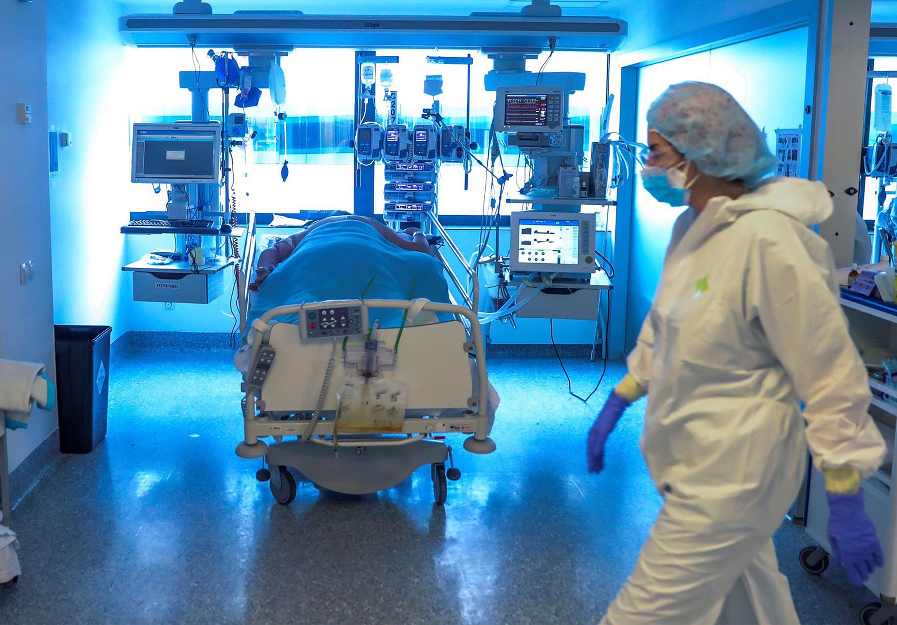 Una sanitaria atiende a un paciente en una UCI de un hospital.