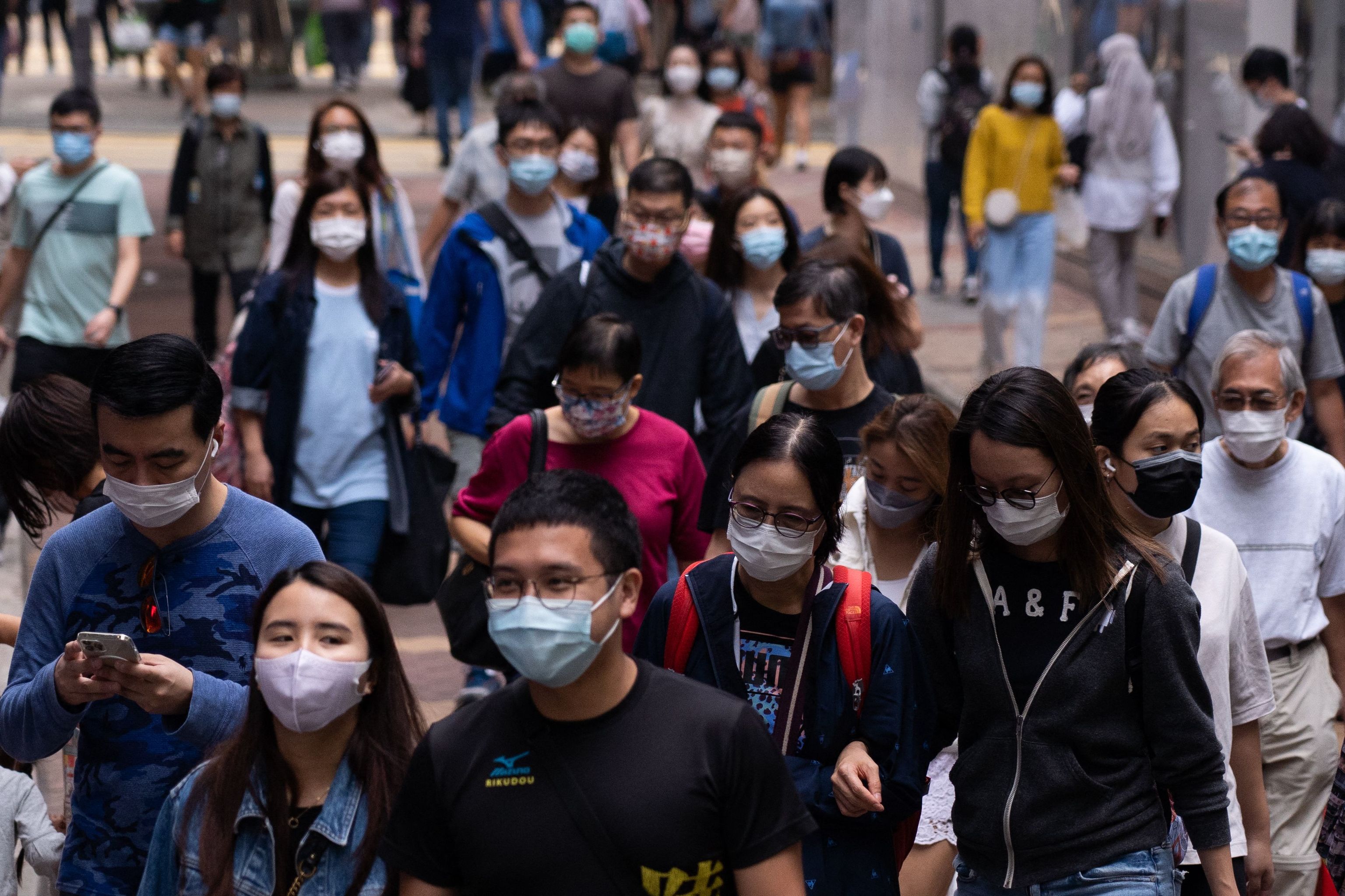 Several people walk wearing masks on a Hong Kong street.