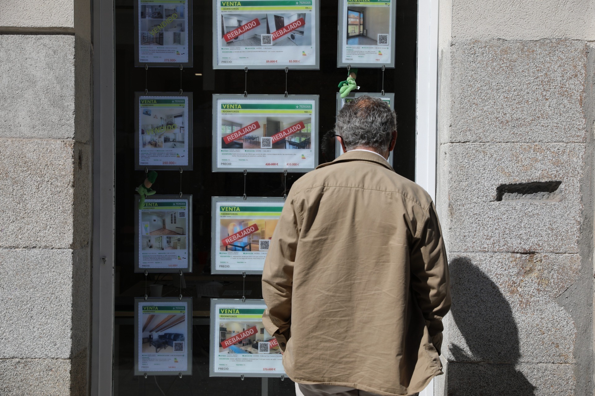Un hombre observa los carteles de venta de una agencia inmobiliaria.