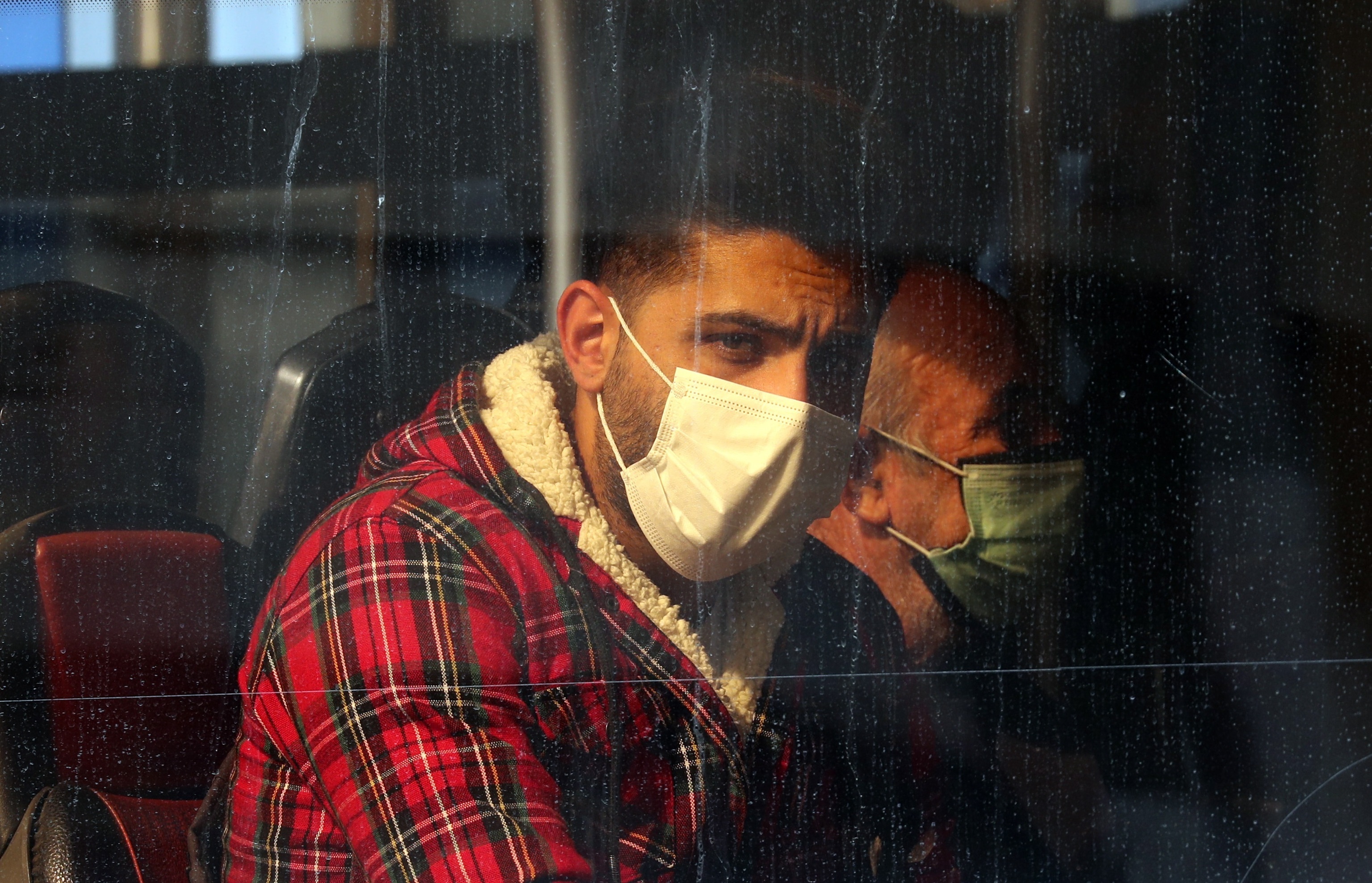 Hombres con mascarilla en un bus de Tehern.