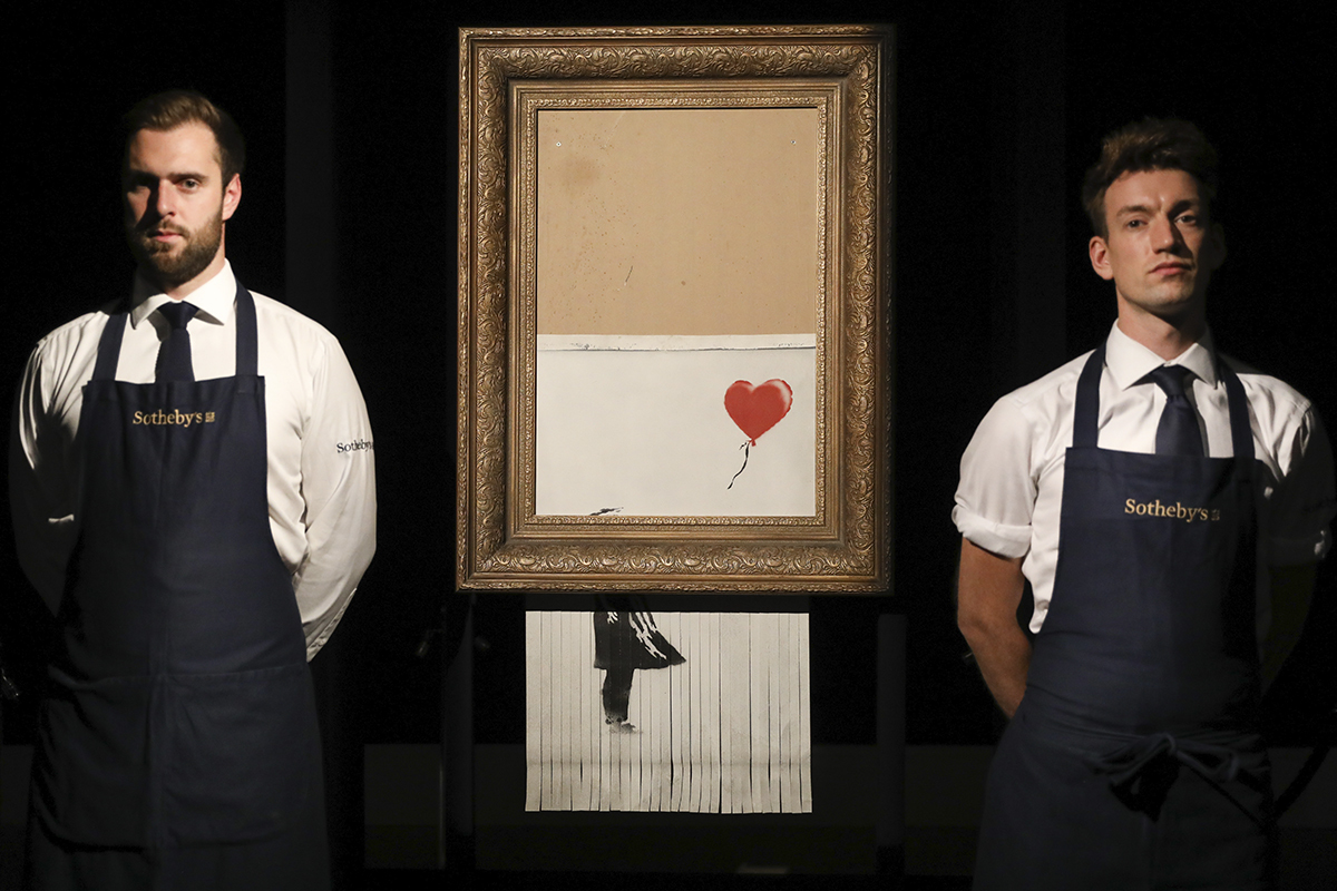 Dos empleados de Sotheby's custodian la obra 'Love is in a Bin', que alcanz 18,5 millones de libras en subasta.