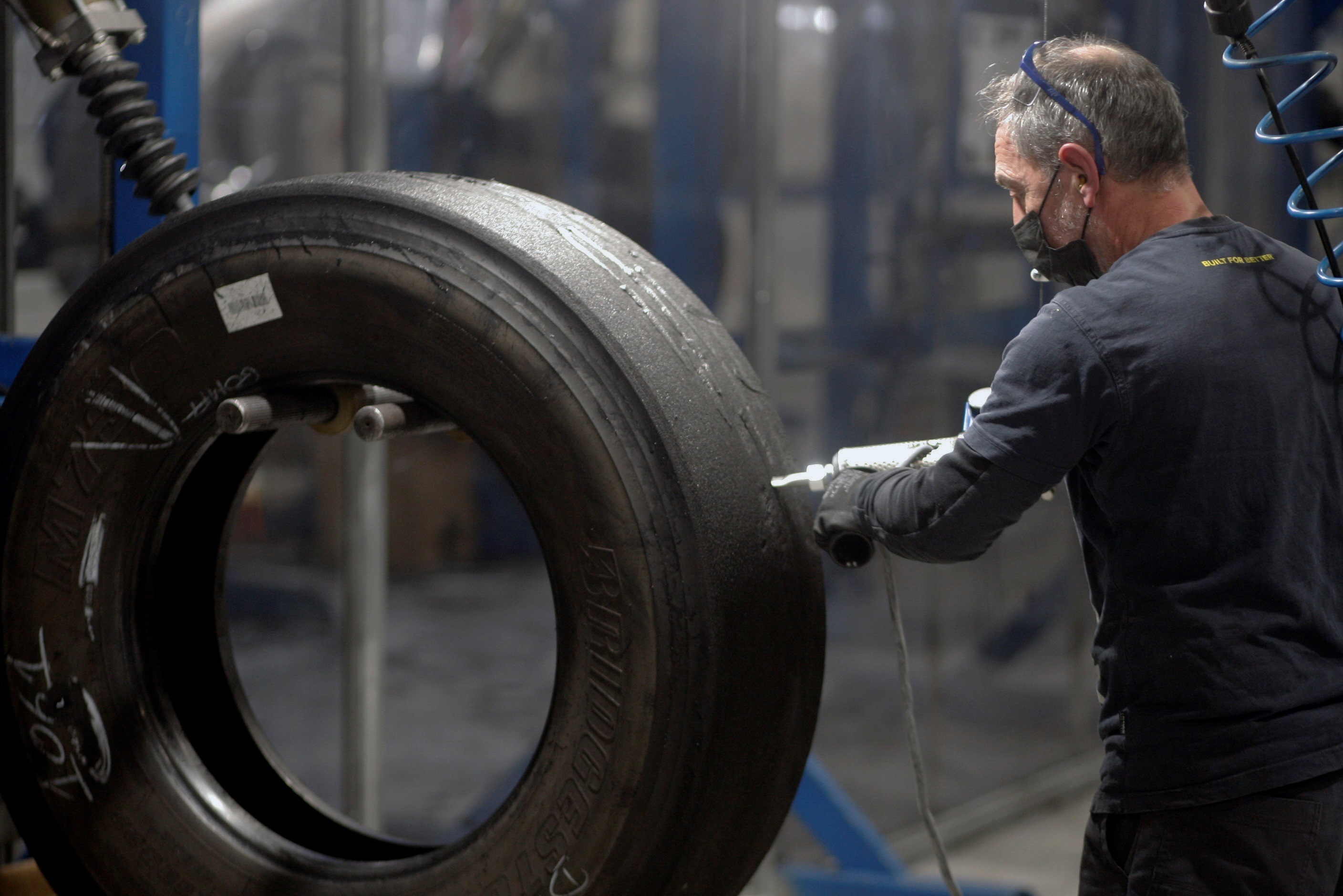 Un operario repara un neumático de camión en un taller en Asturias. EFE/Juan González