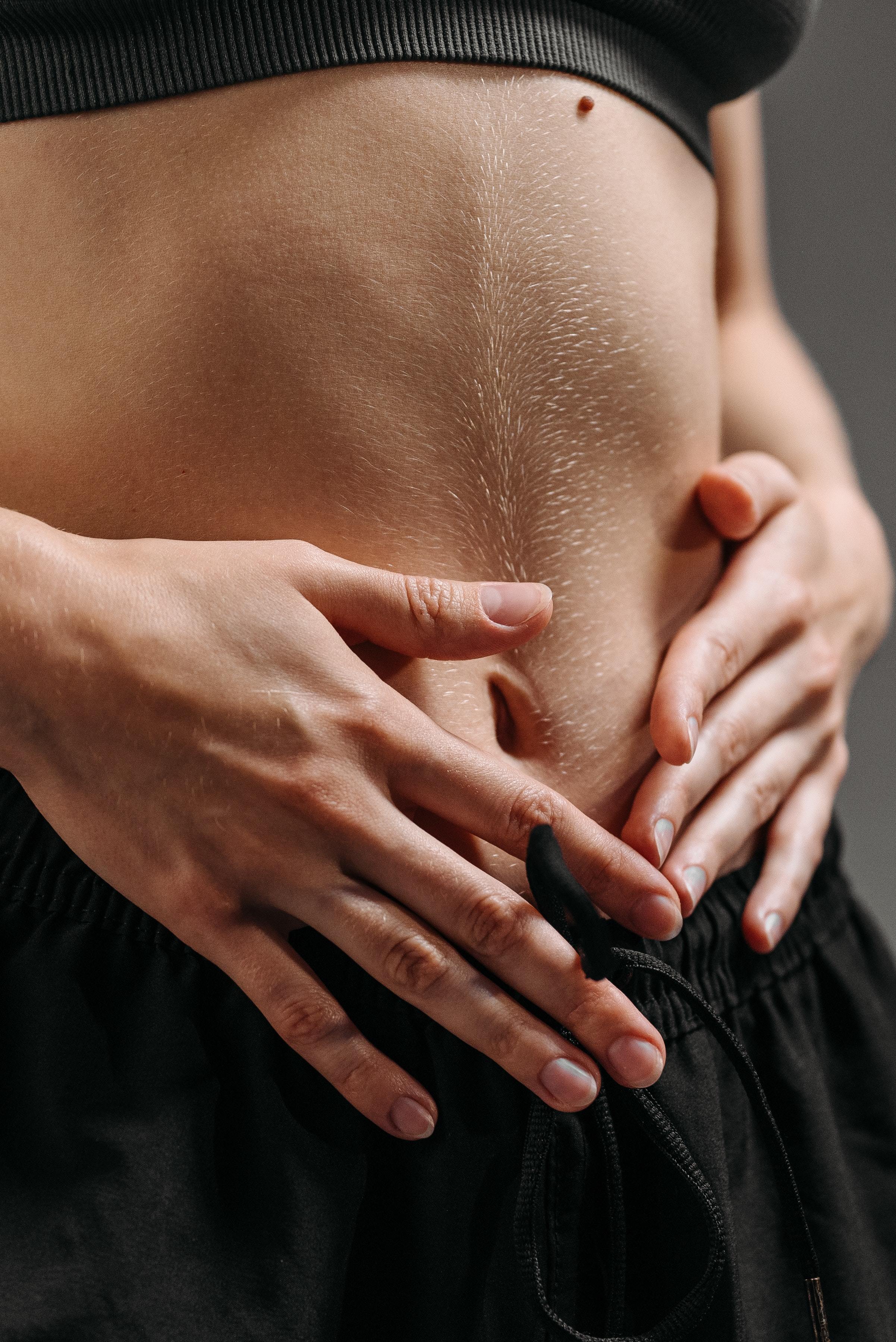 Una mujer toca con sus manos el vientre en señar de dolor de estómago producido por gases.