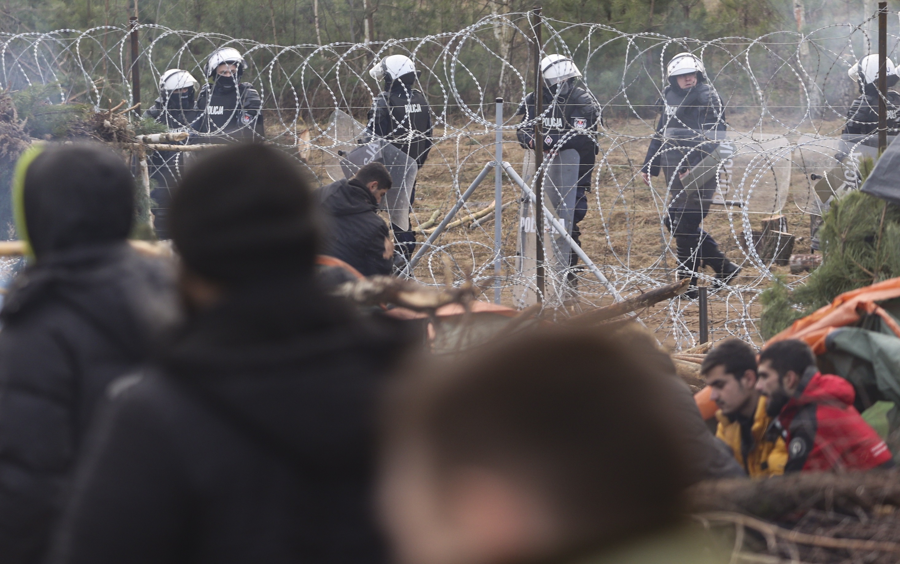 Soldados polacos observan desde su lado de la frontera a los refugiados y migrantes que reciben ayuda humanitaria.
