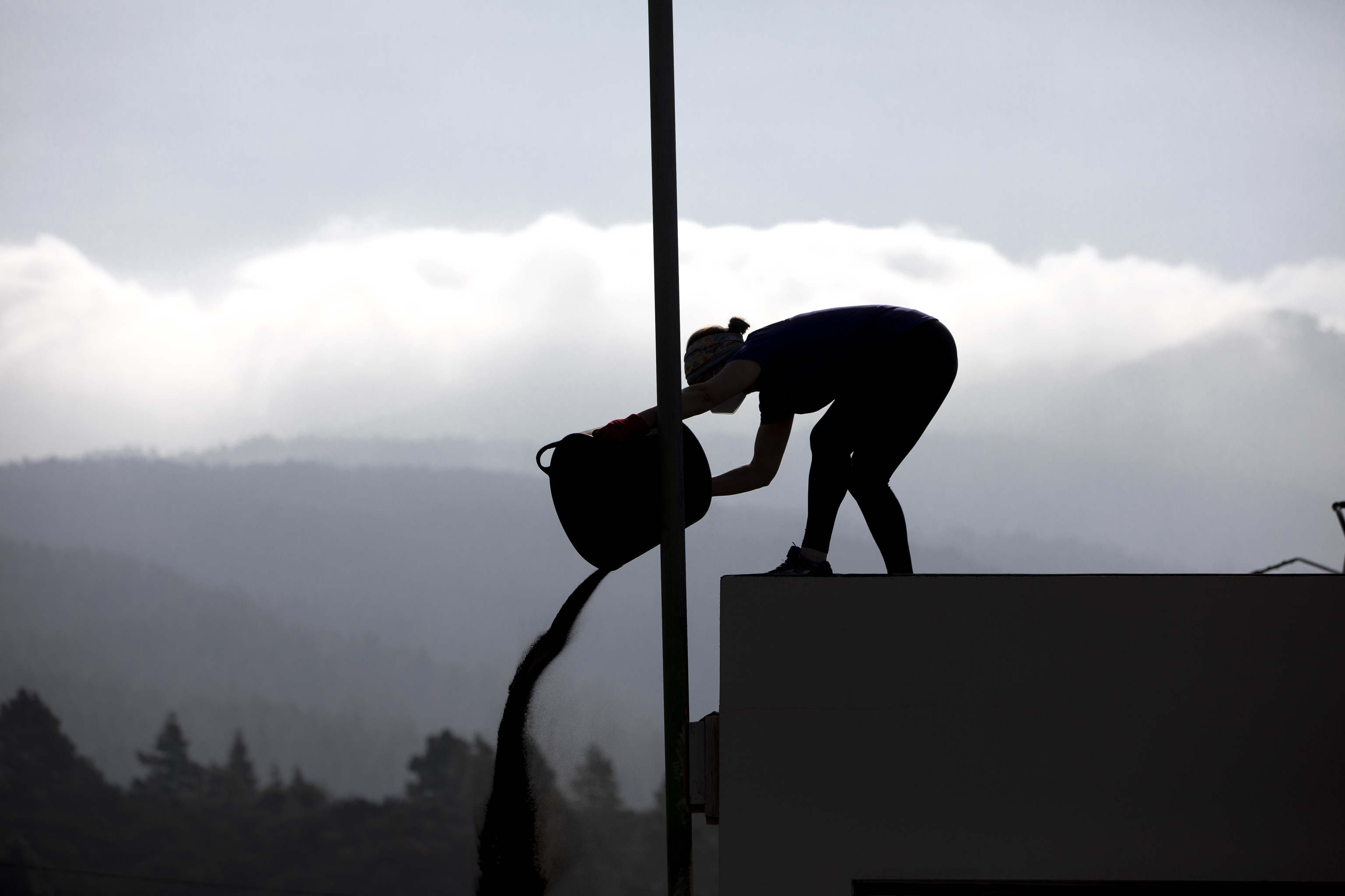 Una mujer limpia ceniza de su tejado en el barrio de Tacande, frente al volcn.