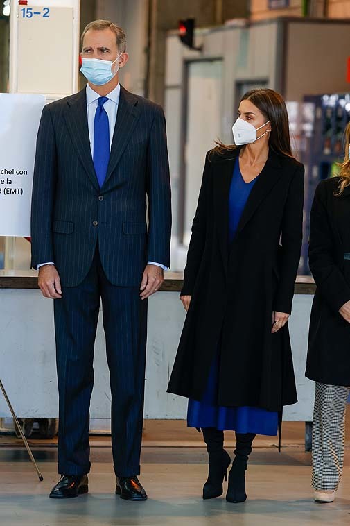 La reina con vestido azul de punto, y abrigo y botas negras.