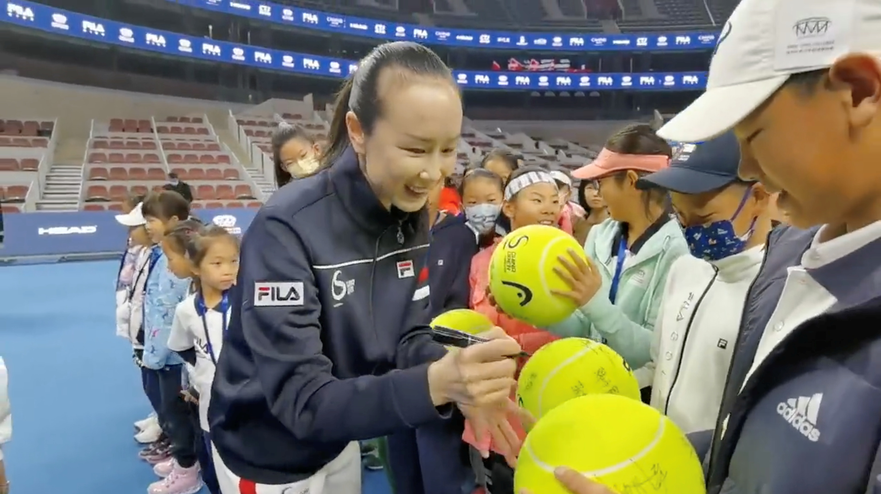 Peng Shuai firma pelotas antes de un torneo juvenil.