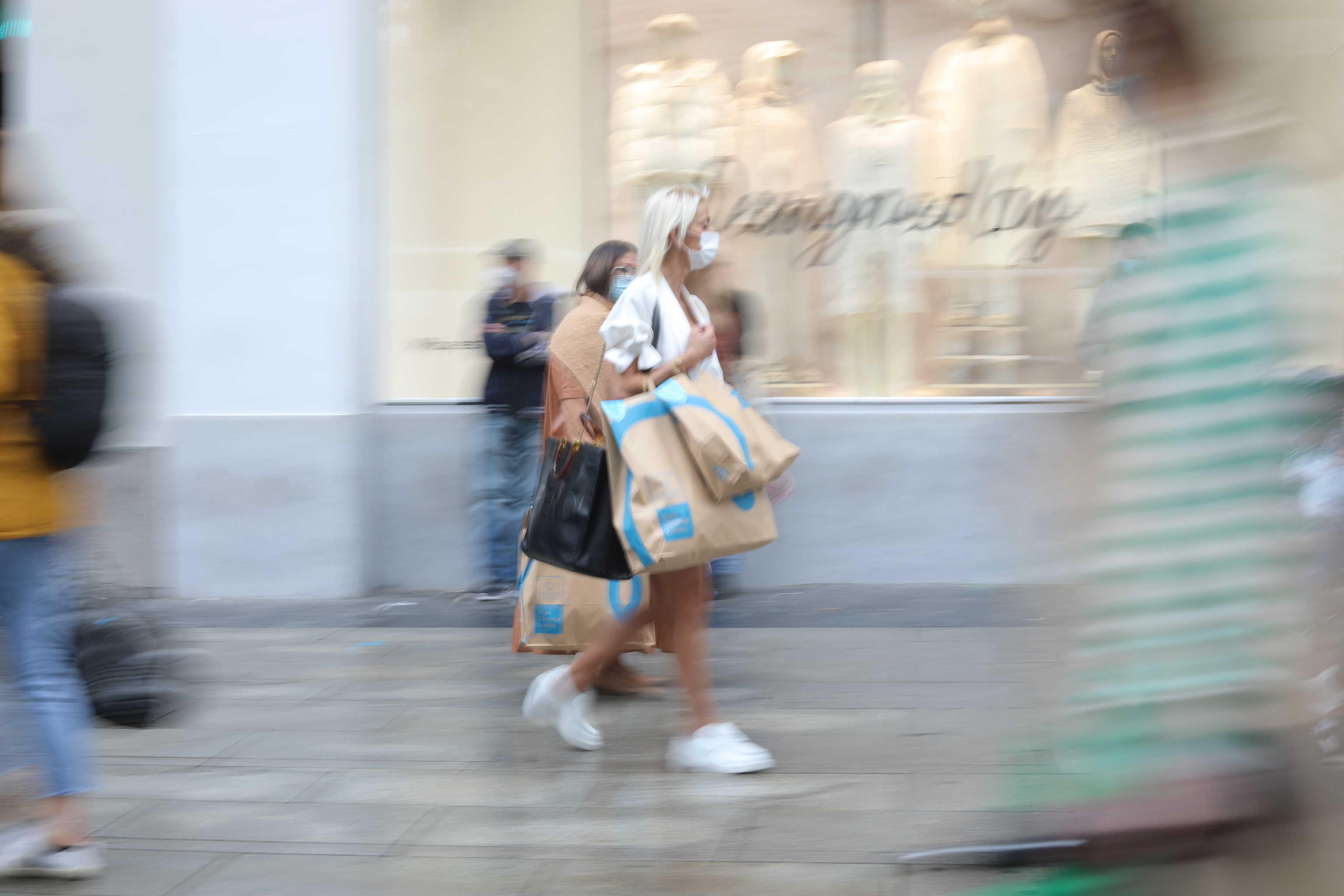 Una mujer, con varias bolsas de tiendas, por una calle de Madrid.
