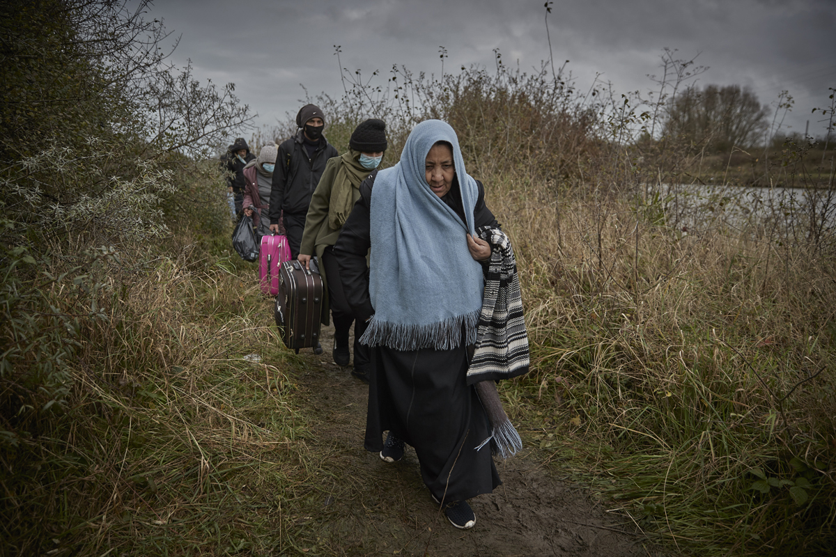 Refugiados caminan con sus pertenencias en Dunkerque.
