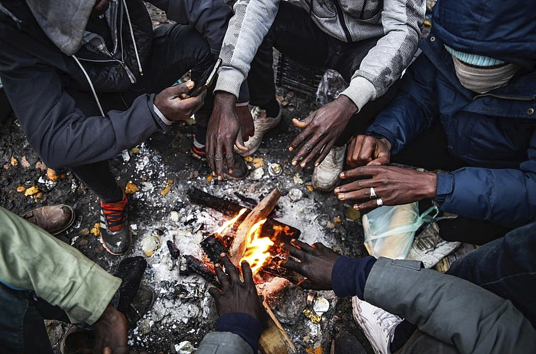 Un grupo de migrantes se calienta frente a una hoguera en Calais.