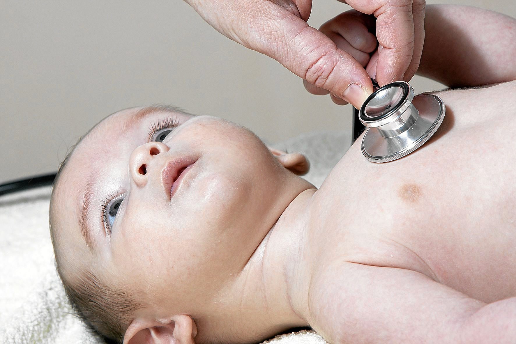 Un pediatra auscultando el pecho a un bebé