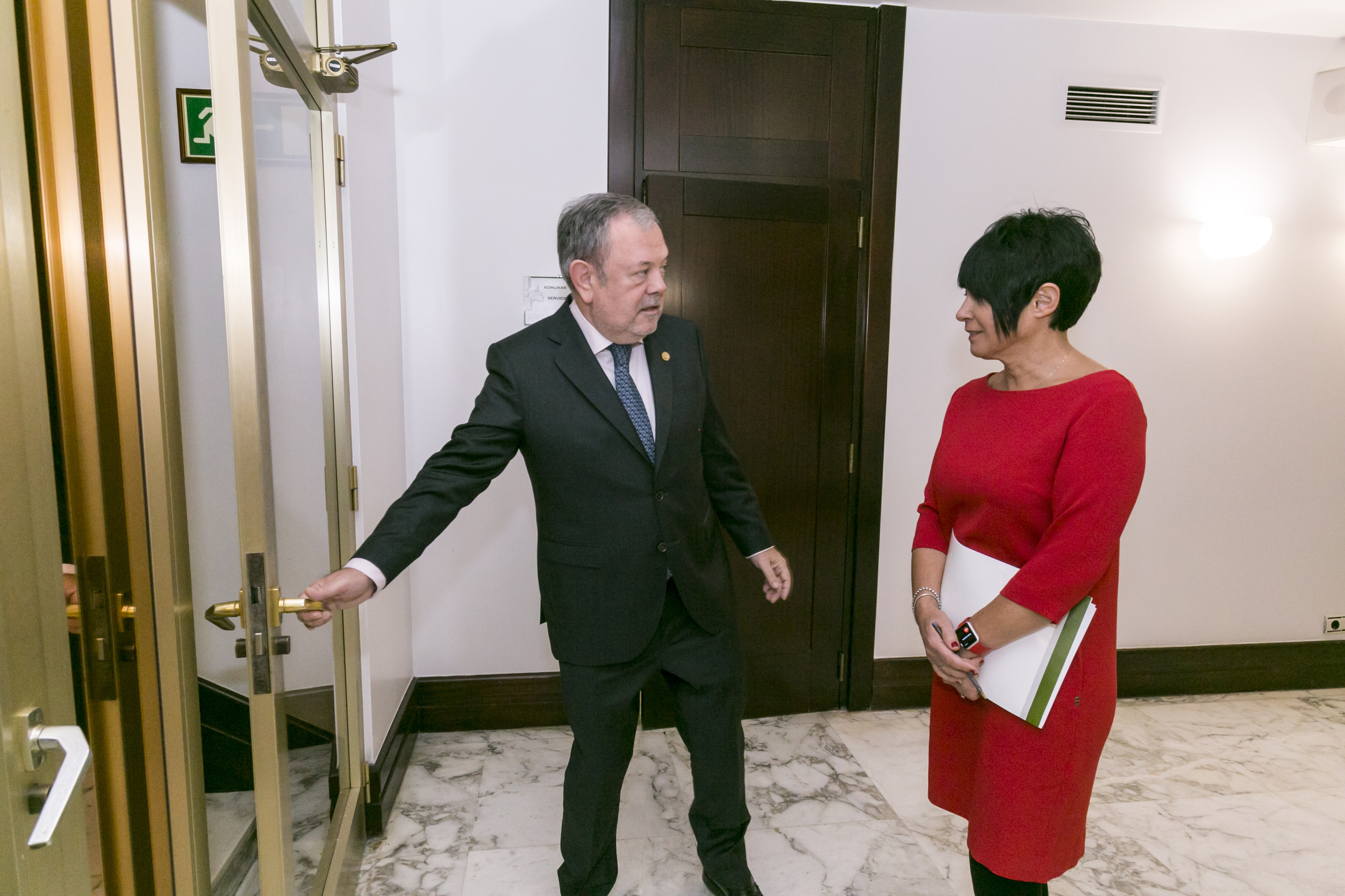 El consejero Pedro Azpiazu abre la puerta de las dependencias del Parlamento Vasco a la portavoz de EH Bildu Maddalen Iriarte.