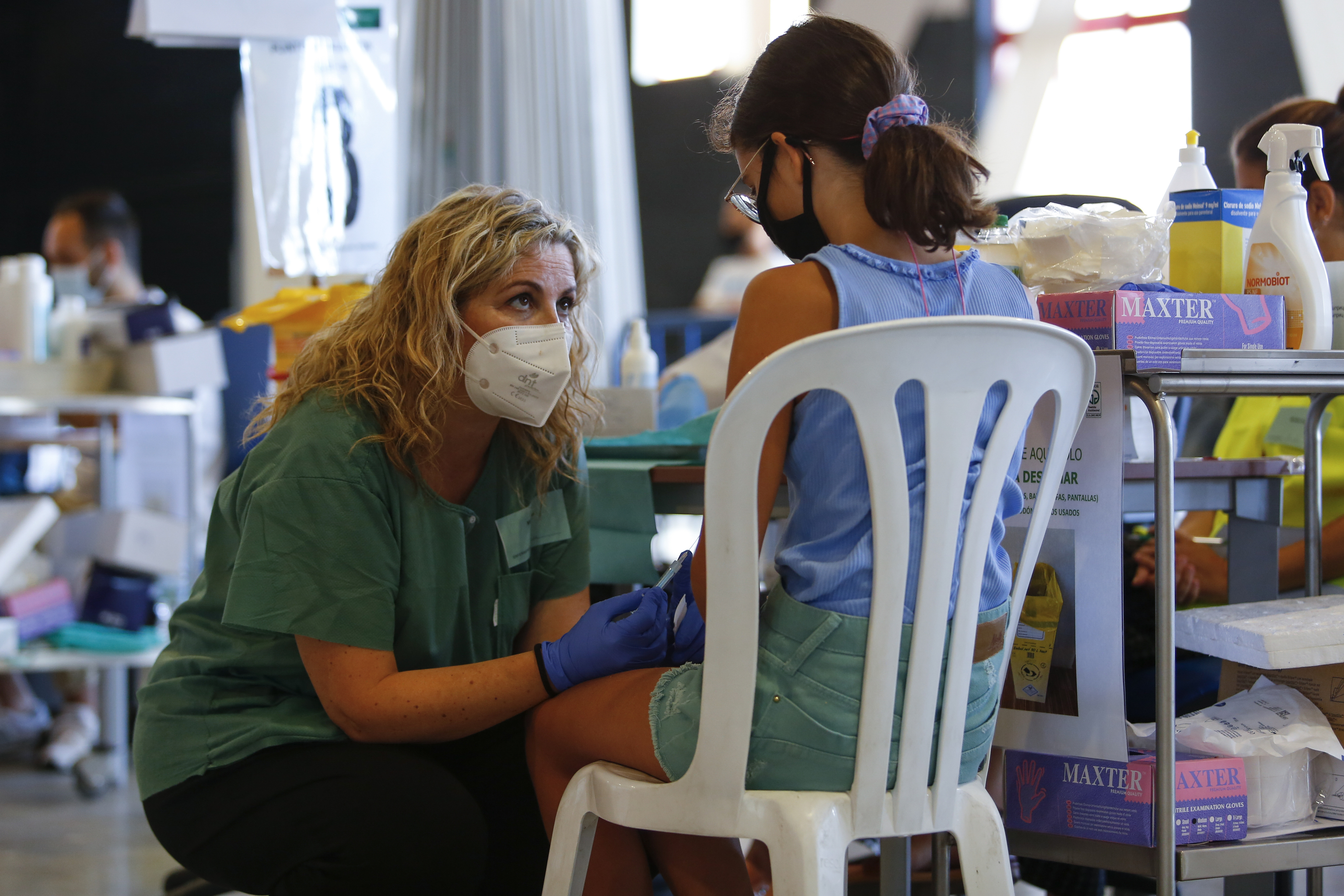 Una enfermera calma a una niña que se va a vacunar frente al Covid en Granada.