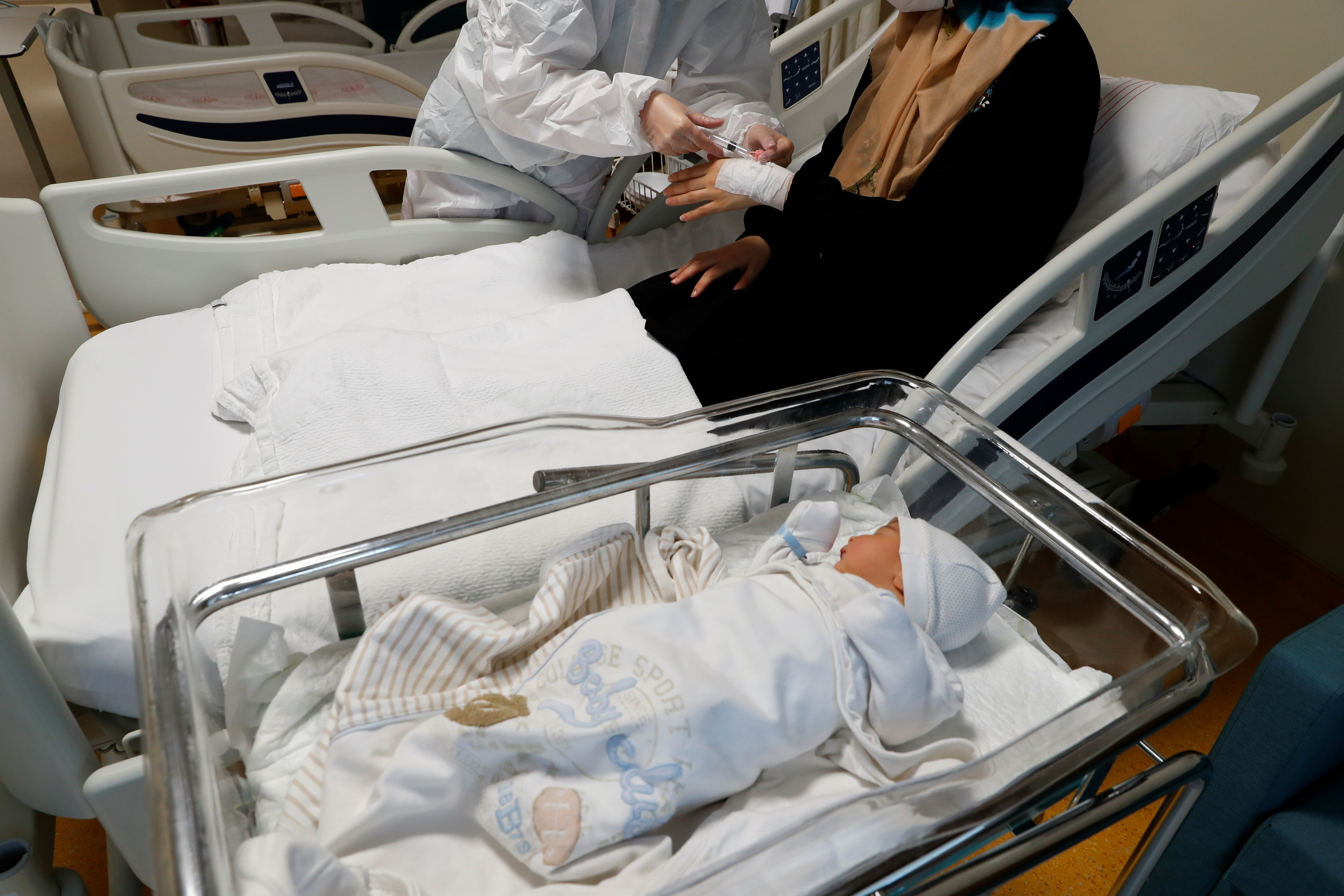 Un sanitario atiende a una mujer enferma de coronavirus junto a su bebé de cuatro días en un hospital de Estambul.