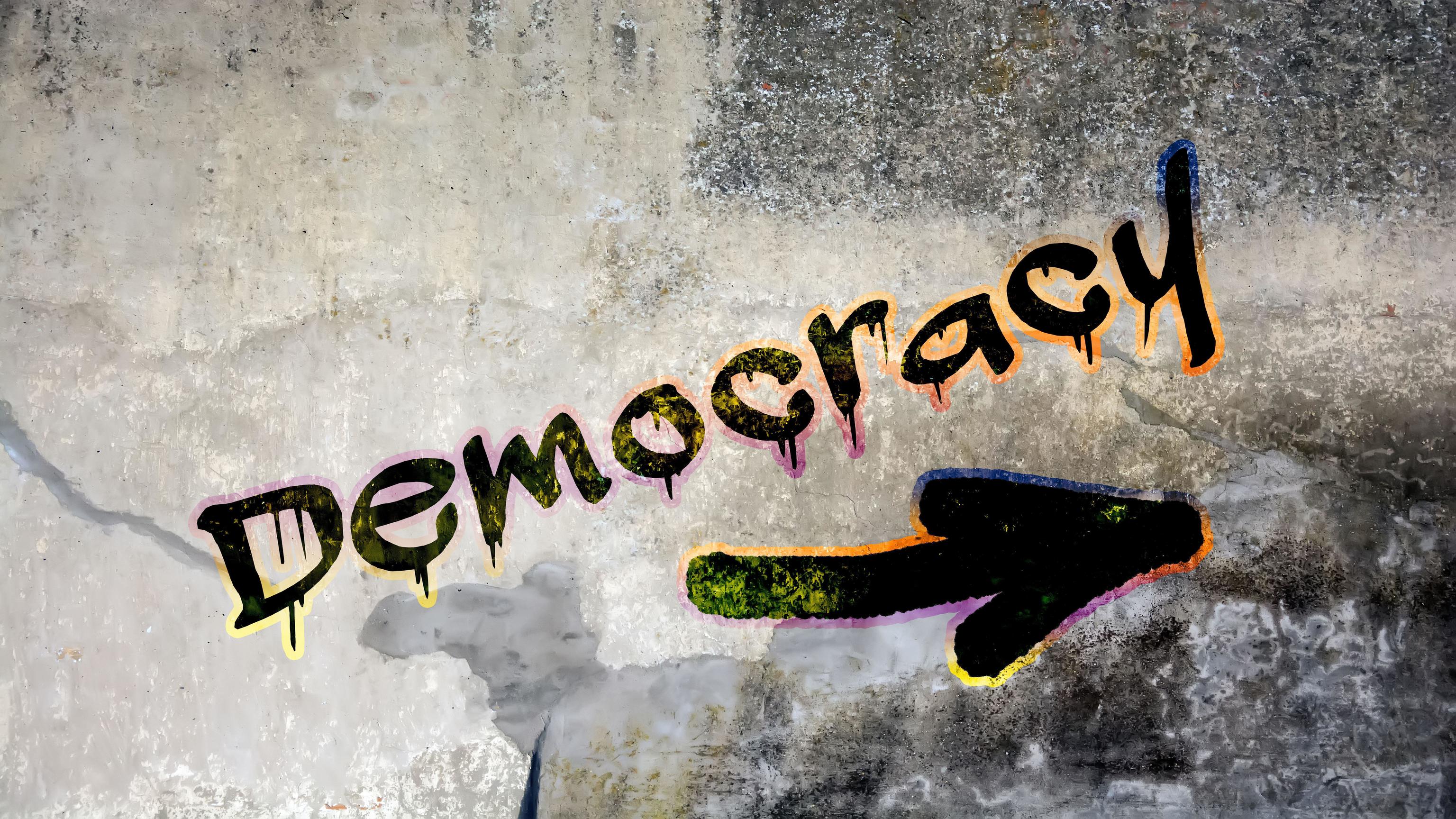 Un grafiti con la palabra 'democracia'.