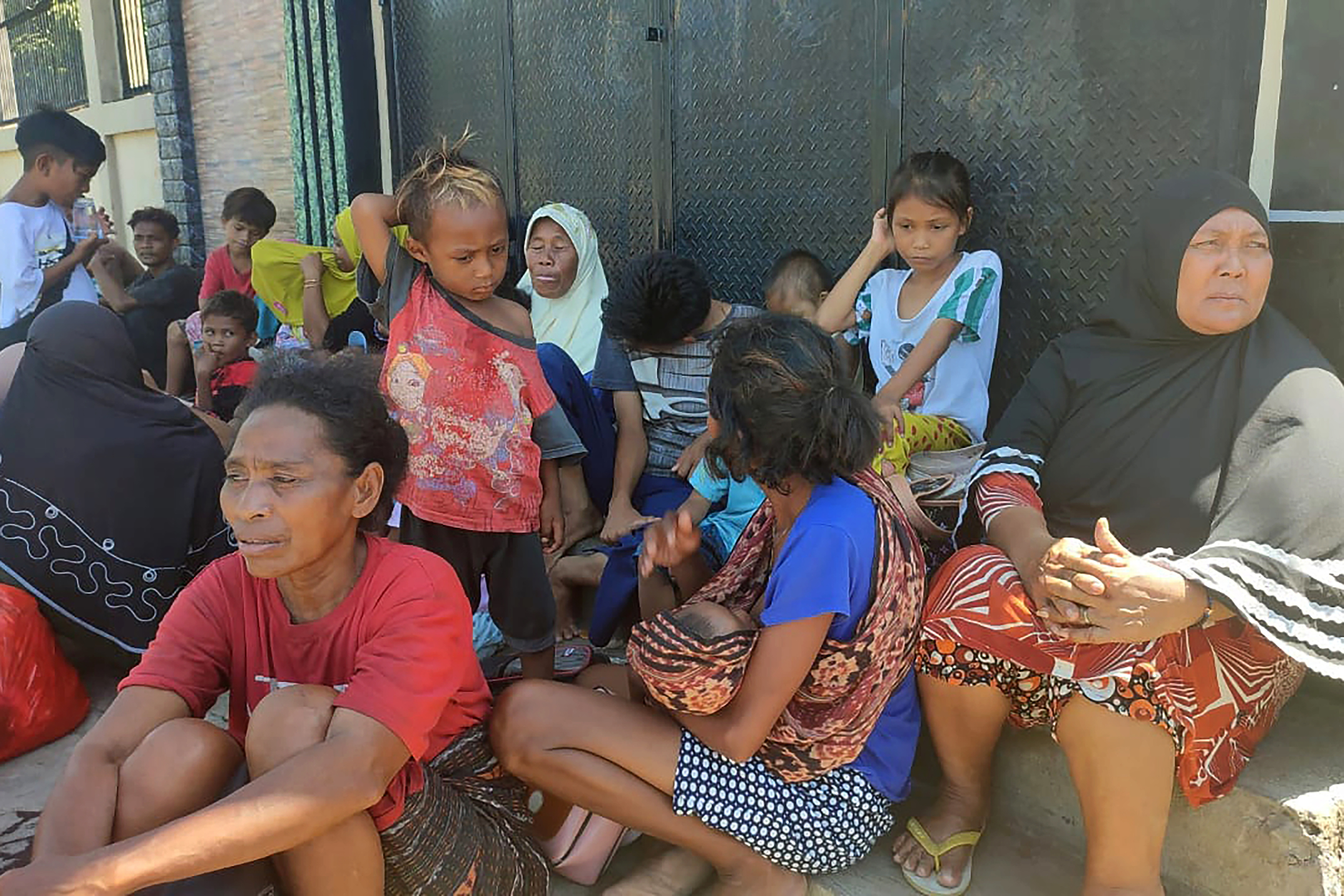 Un grupo de personas espera, en la calle, en Maumere (Indonesia).
