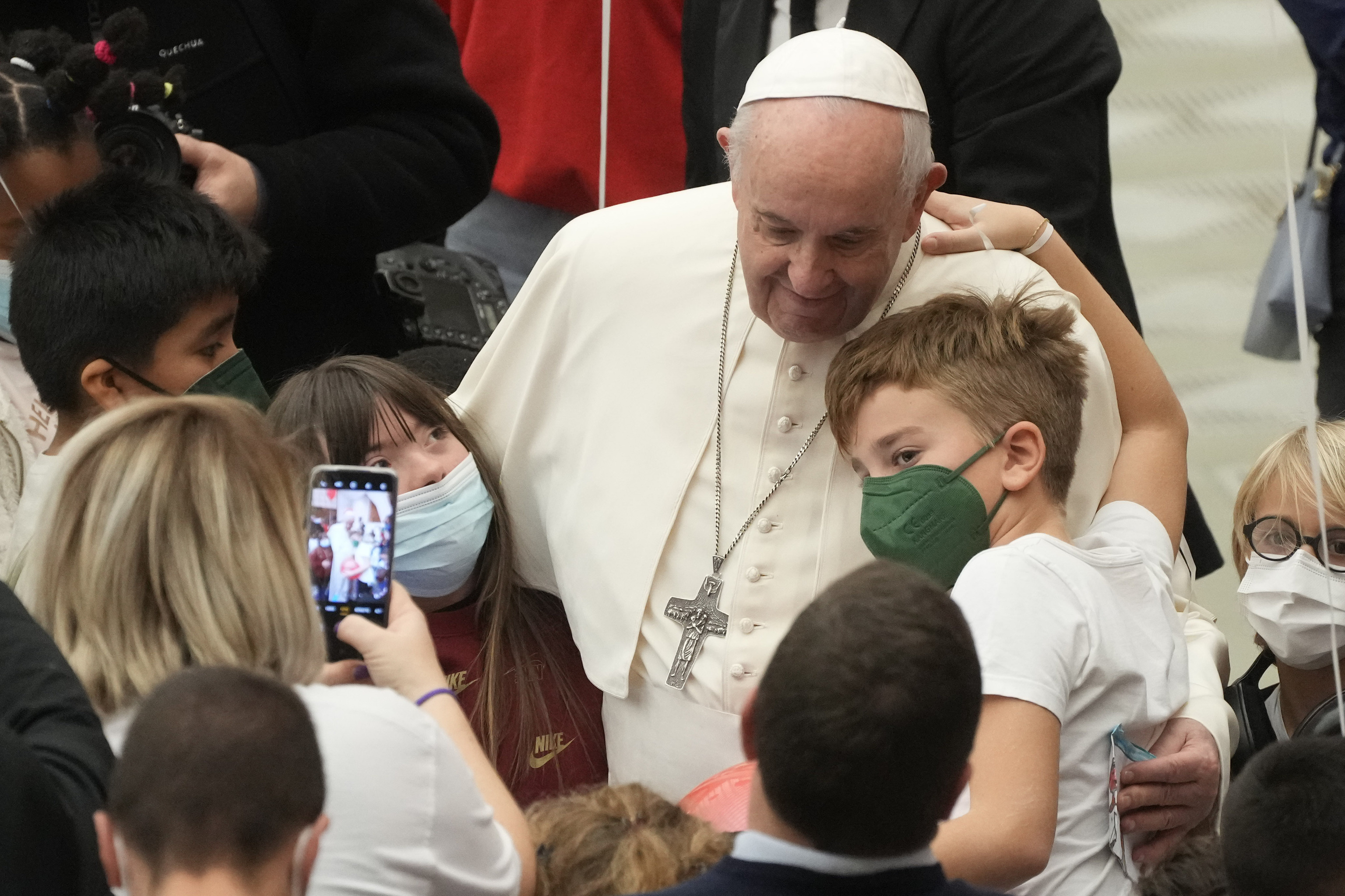 Varis nios abrazan al Papa Francisco, en el Vaticano.