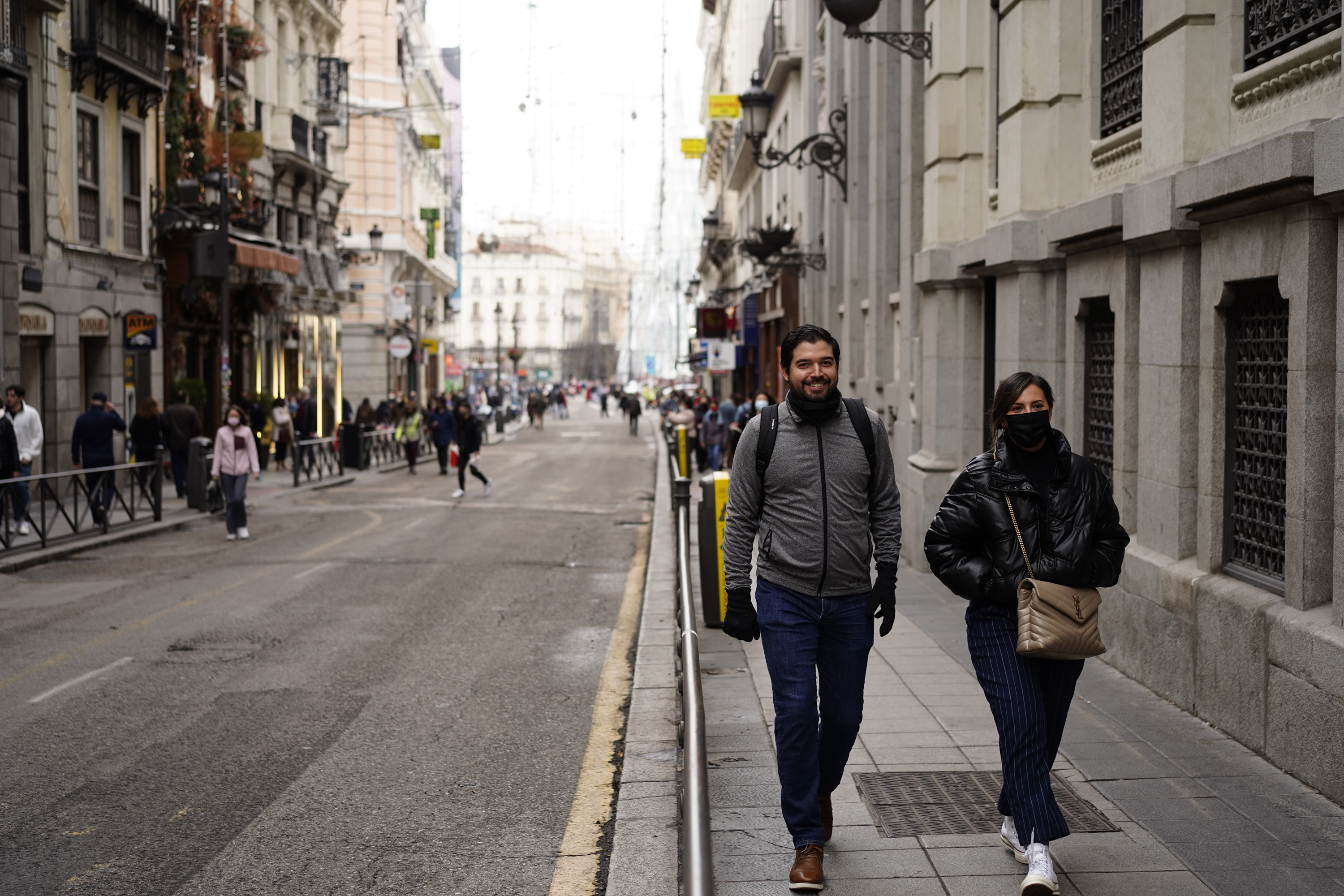 Dos paseantes por la Carrera de San Jernimo, con la Puerta del Sol a la espalda.