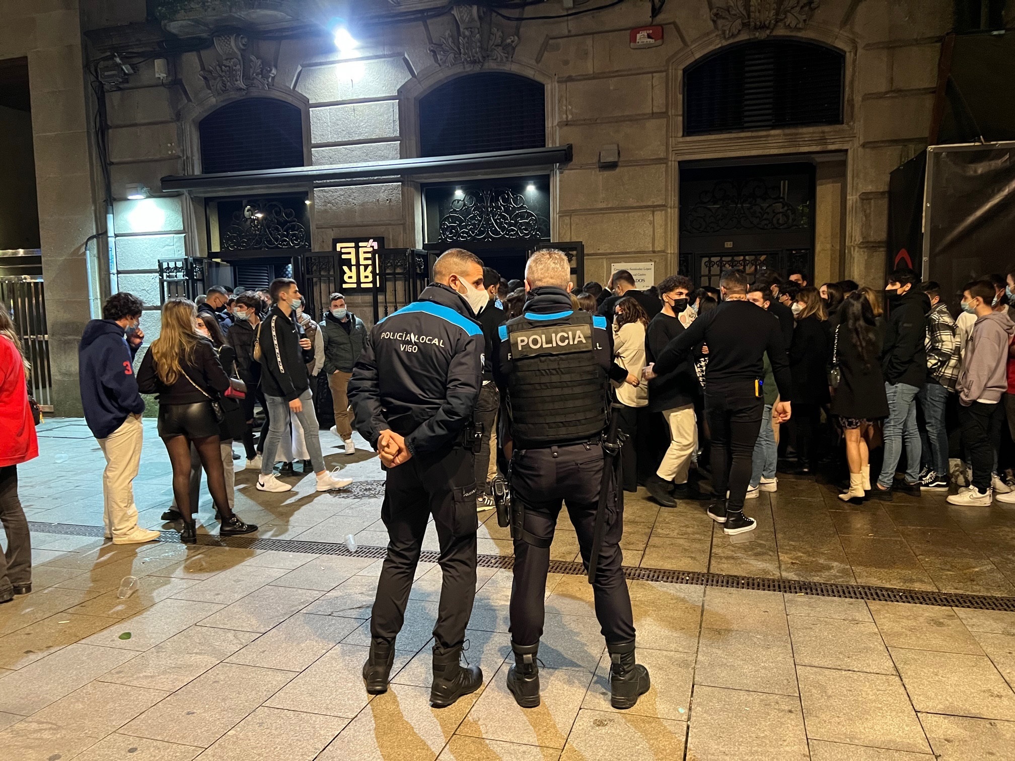 Dos policas locales vigilan aun grupo de jvenes congregados alrededor de un local de ocio nocturno la pasada noche en Vigo.