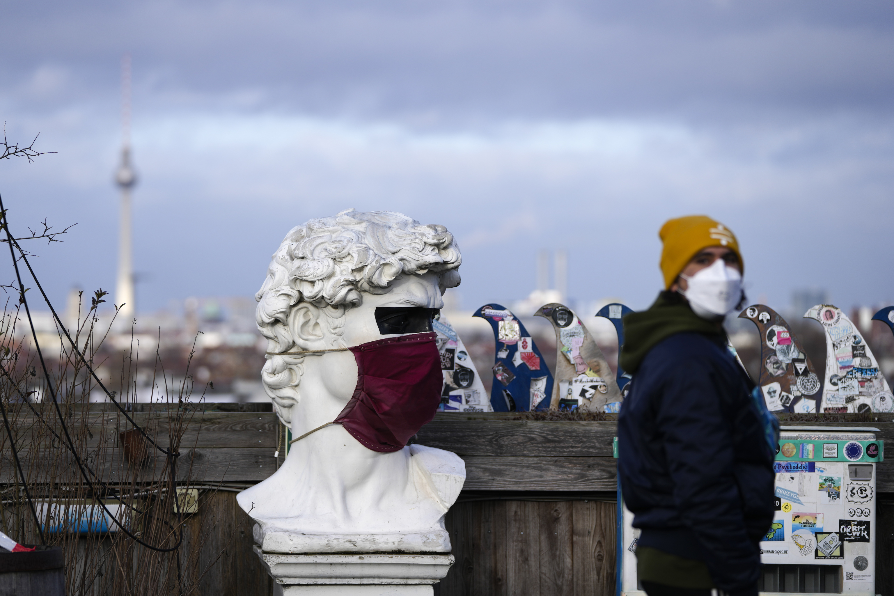 Un hombre junto a una estatua con mascarilla en Berln.