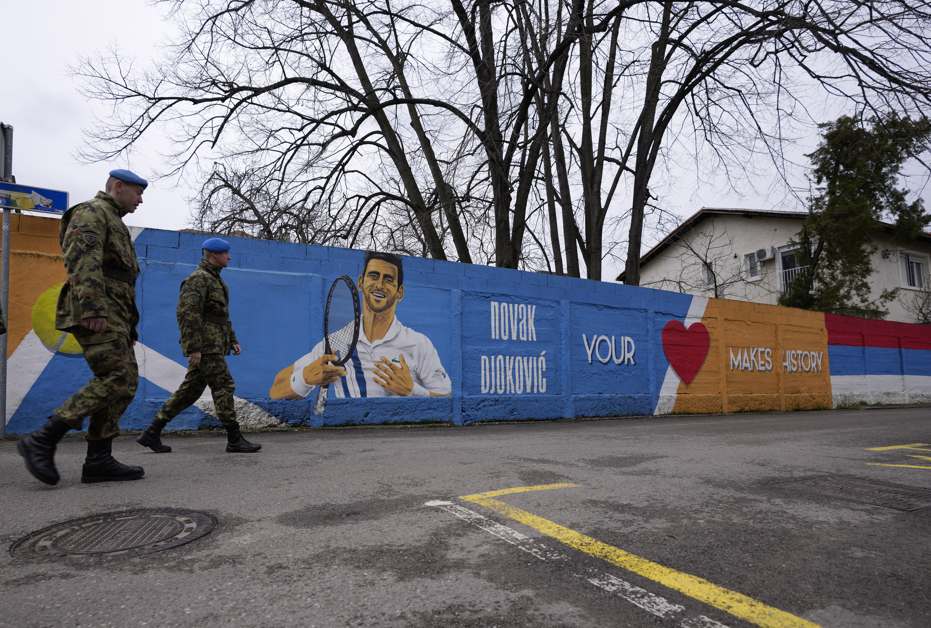 Soldados serbios pasan junto a un mural en Belgrado en honor a Djokovic.
