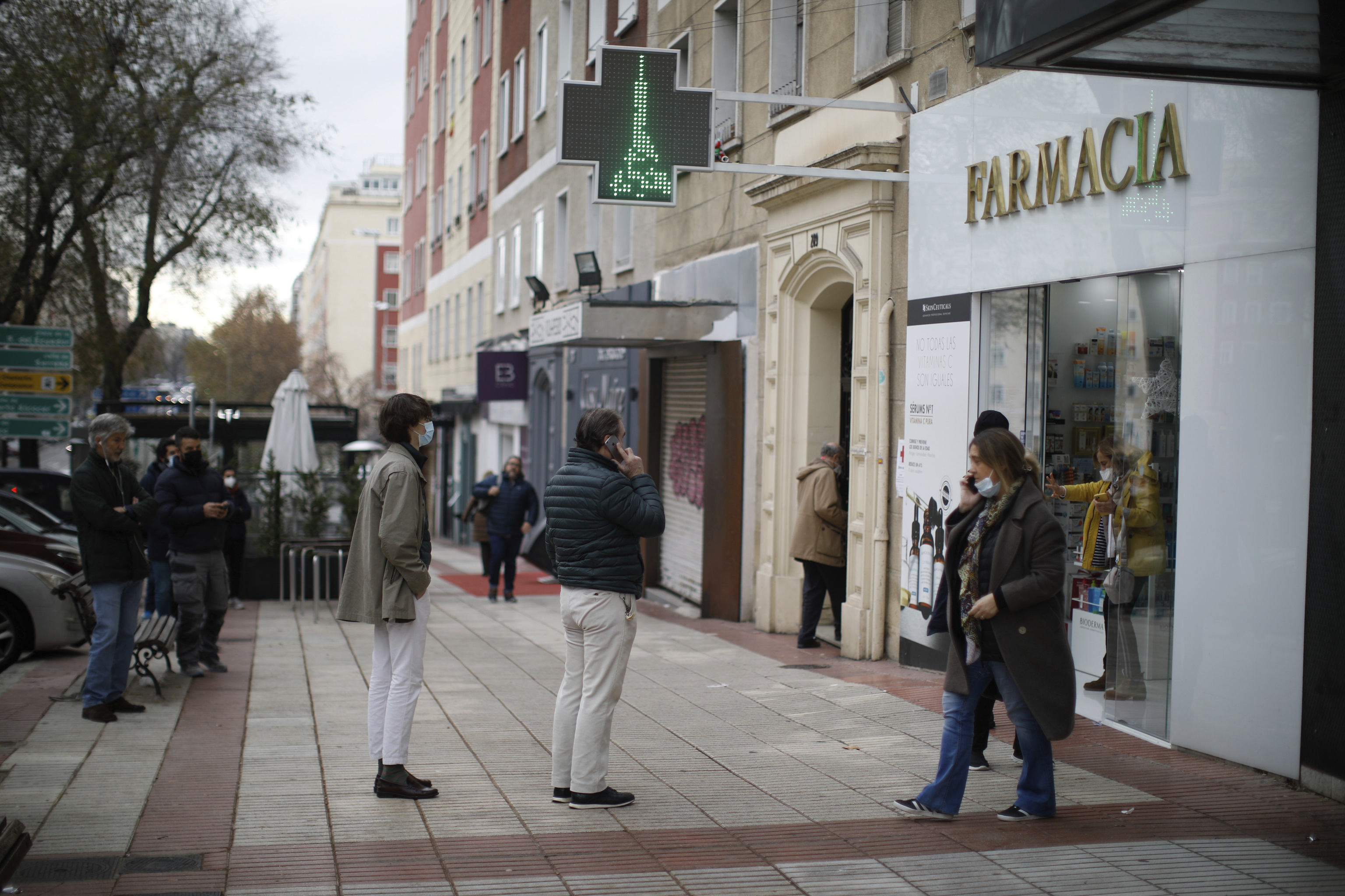 Varias personas hacen cola frente a una farmacia de Madrid para conseguir test de antgenos.