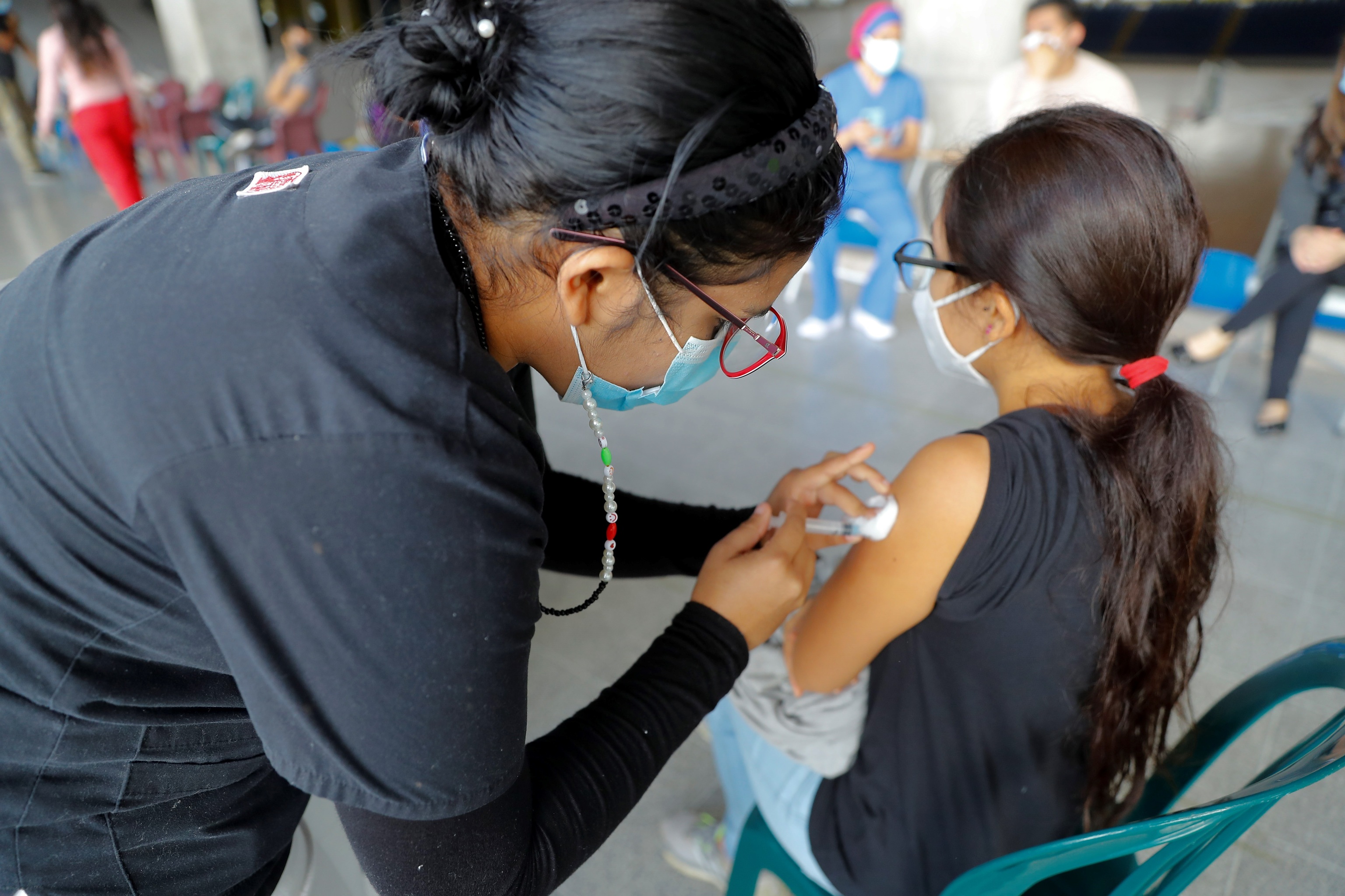 Una trabajadora de la Salud vacuna a una menor de edad.