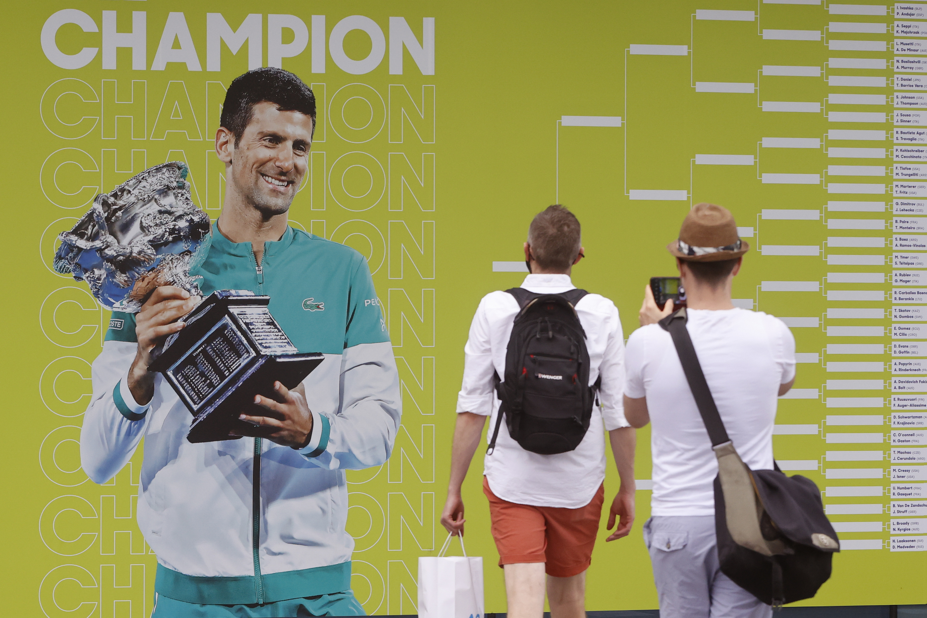 Fans toman fotografas del cuadro del torneo con la imagen de Djokovic como vigente campen.