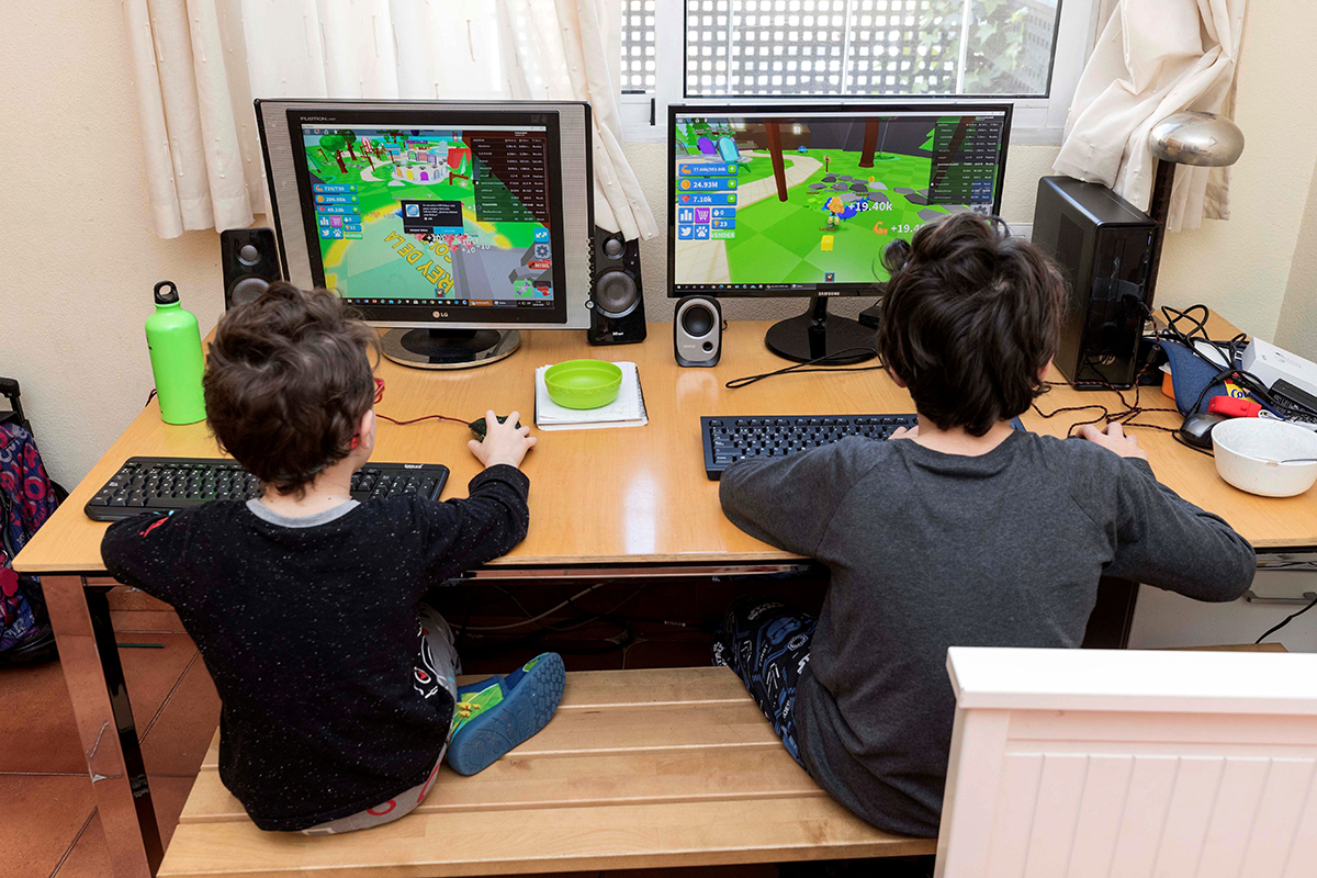Dos niños juegan en sus ordenadores.
