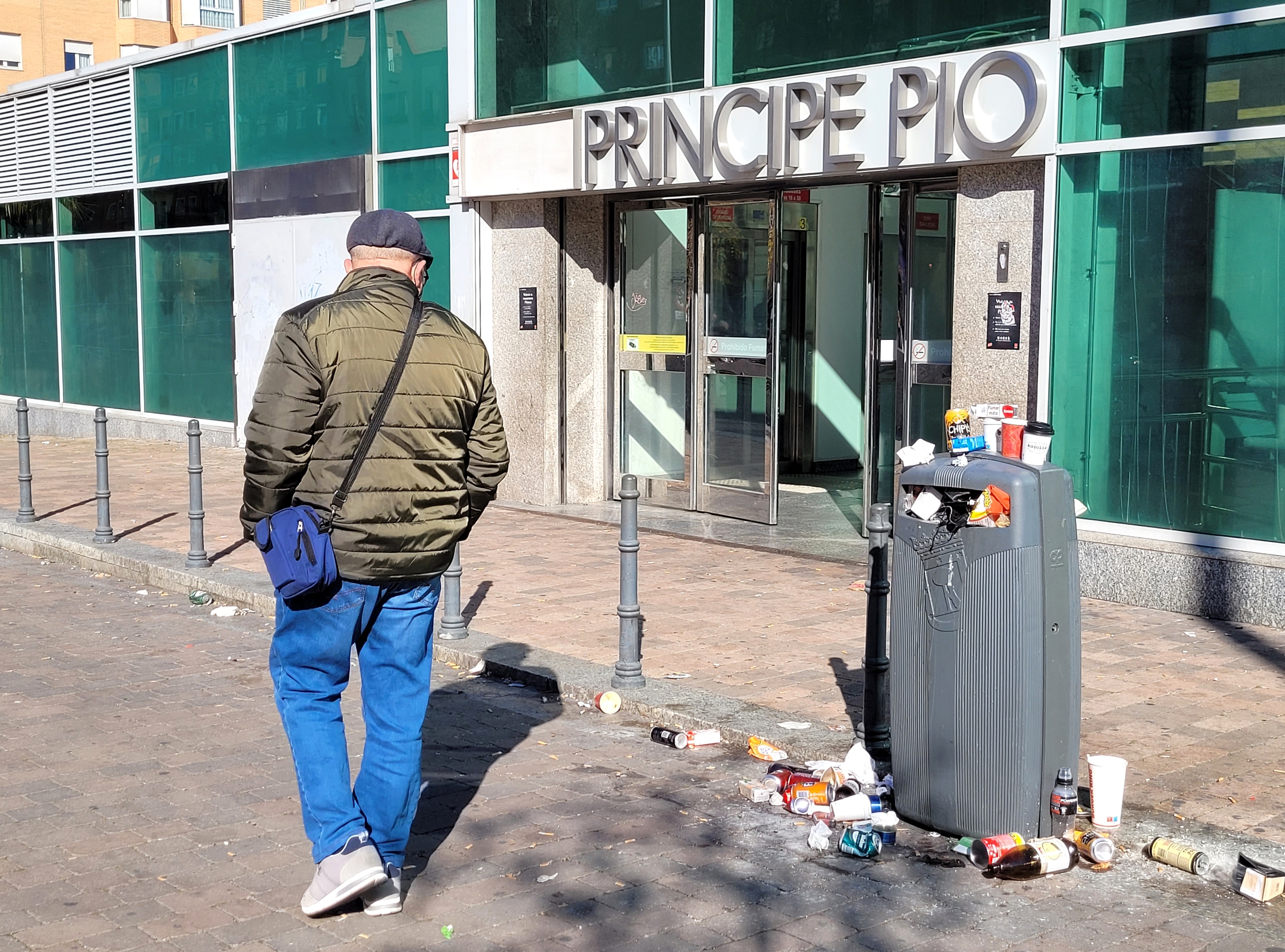 Un viandante se queda mirando la basura acumulada frente a una entrada de la estación de Príncipe Pío.
