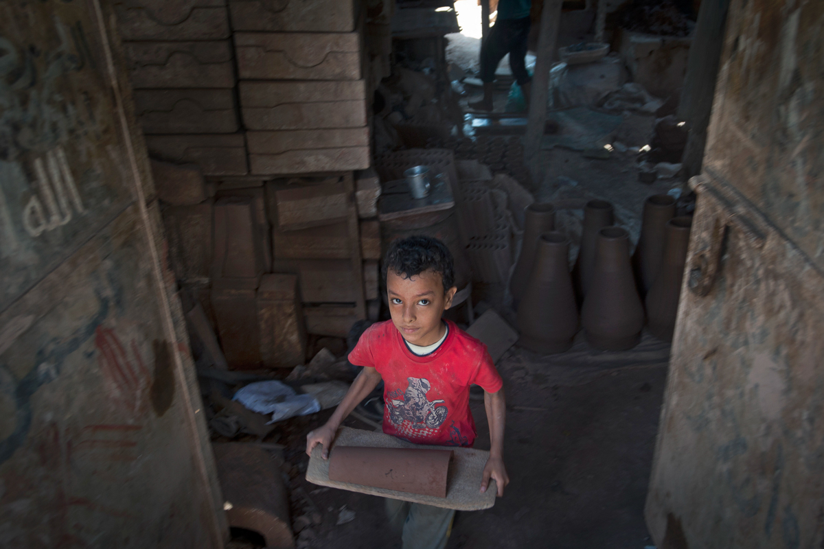 A minor carries clay tiles in a workshop in the old city of Cairo.