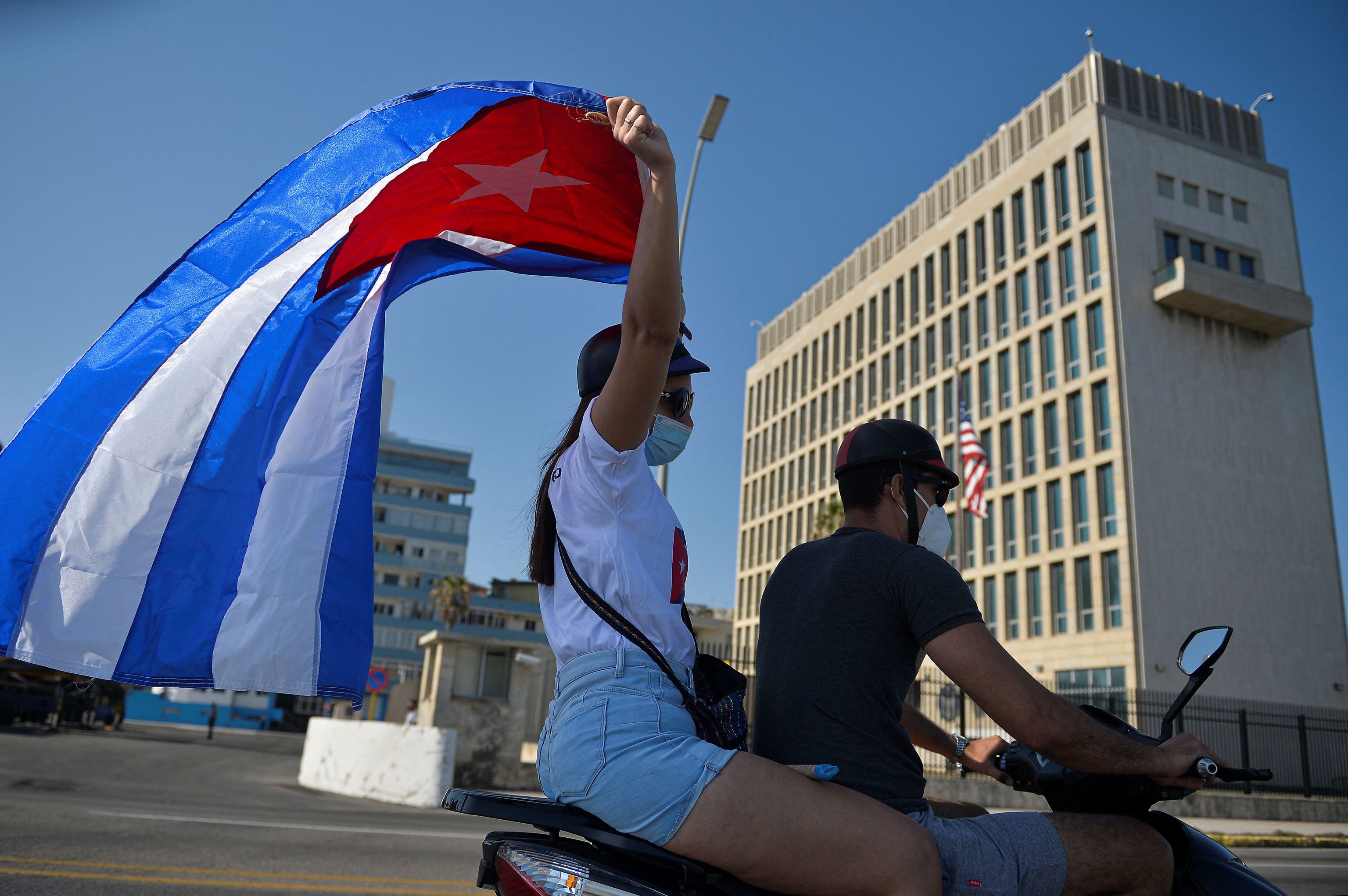 Cubanos pasan junto a la embajada de EEUU en La Habana.