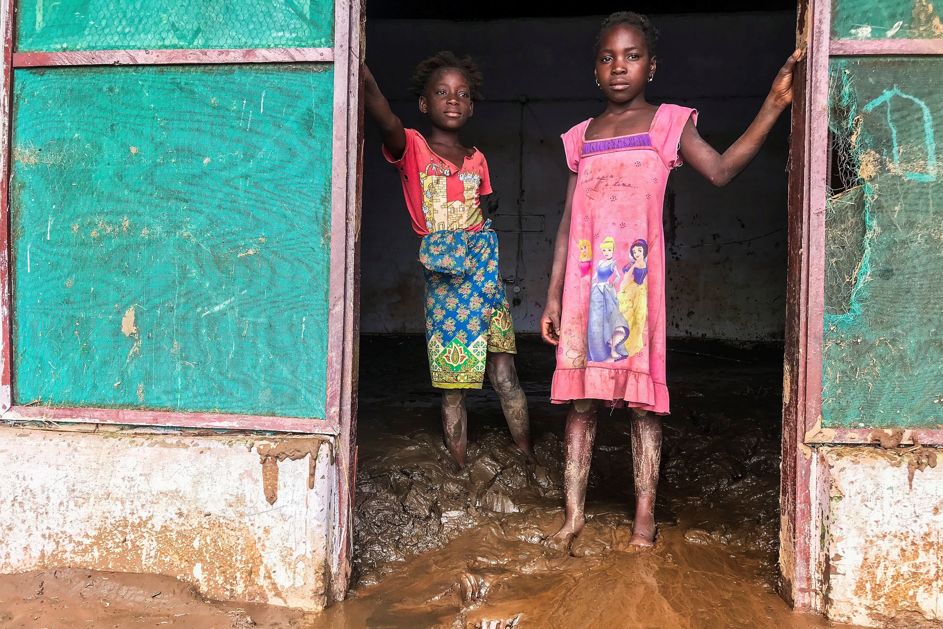 Dos niños con las piernas hundidas en el barro, en Tete (Mozambique).