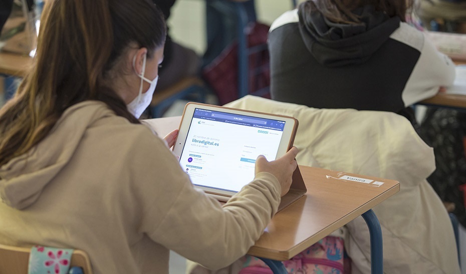 Una alumna atiende una clase con una tableta digital.