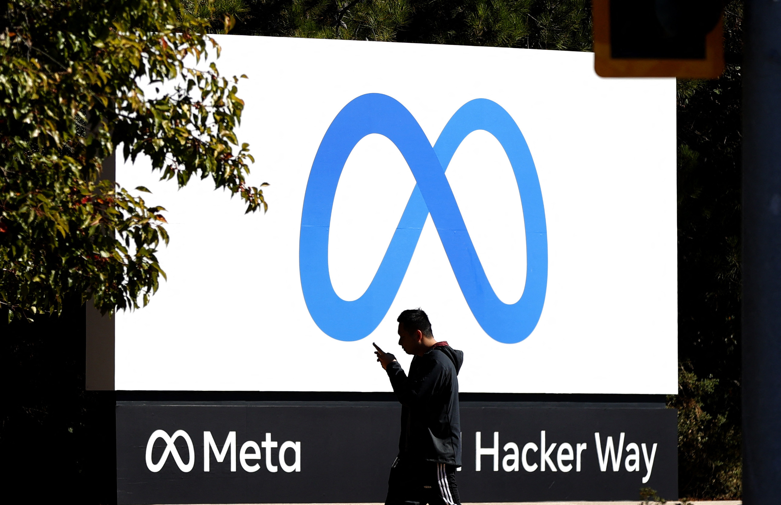 Una persona camina delante de un logo de Meta.
