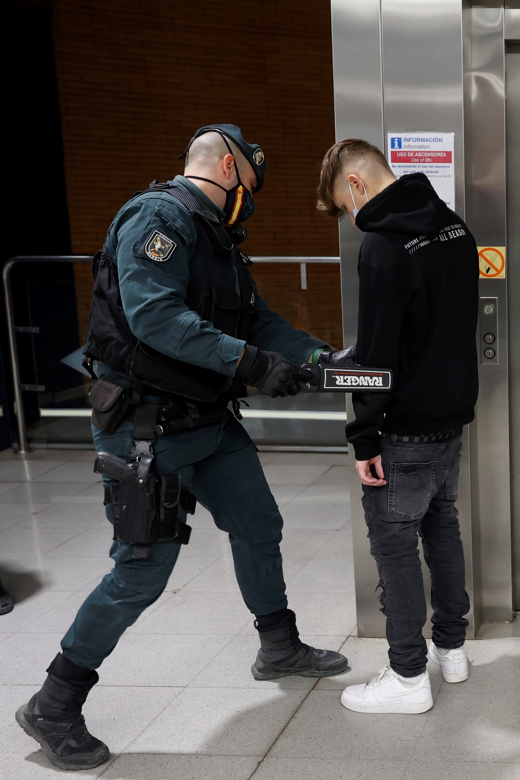 Un agente de la Guardia Civil pasando el detector de metales a un joven en el metro de Arganda del Rey hoy viernes.