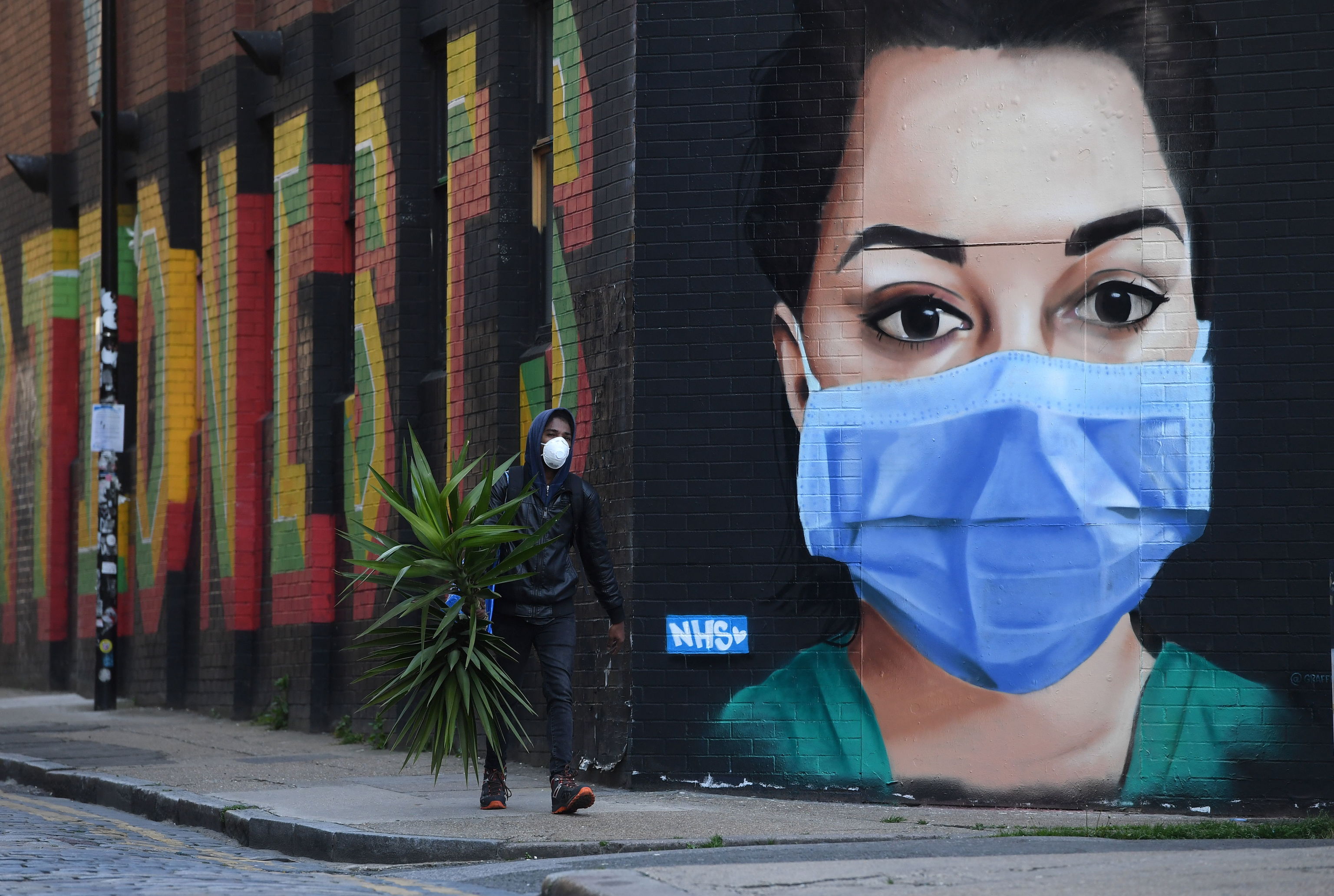Un hombre pasea junto a un mural que homenajea a los sanitarios