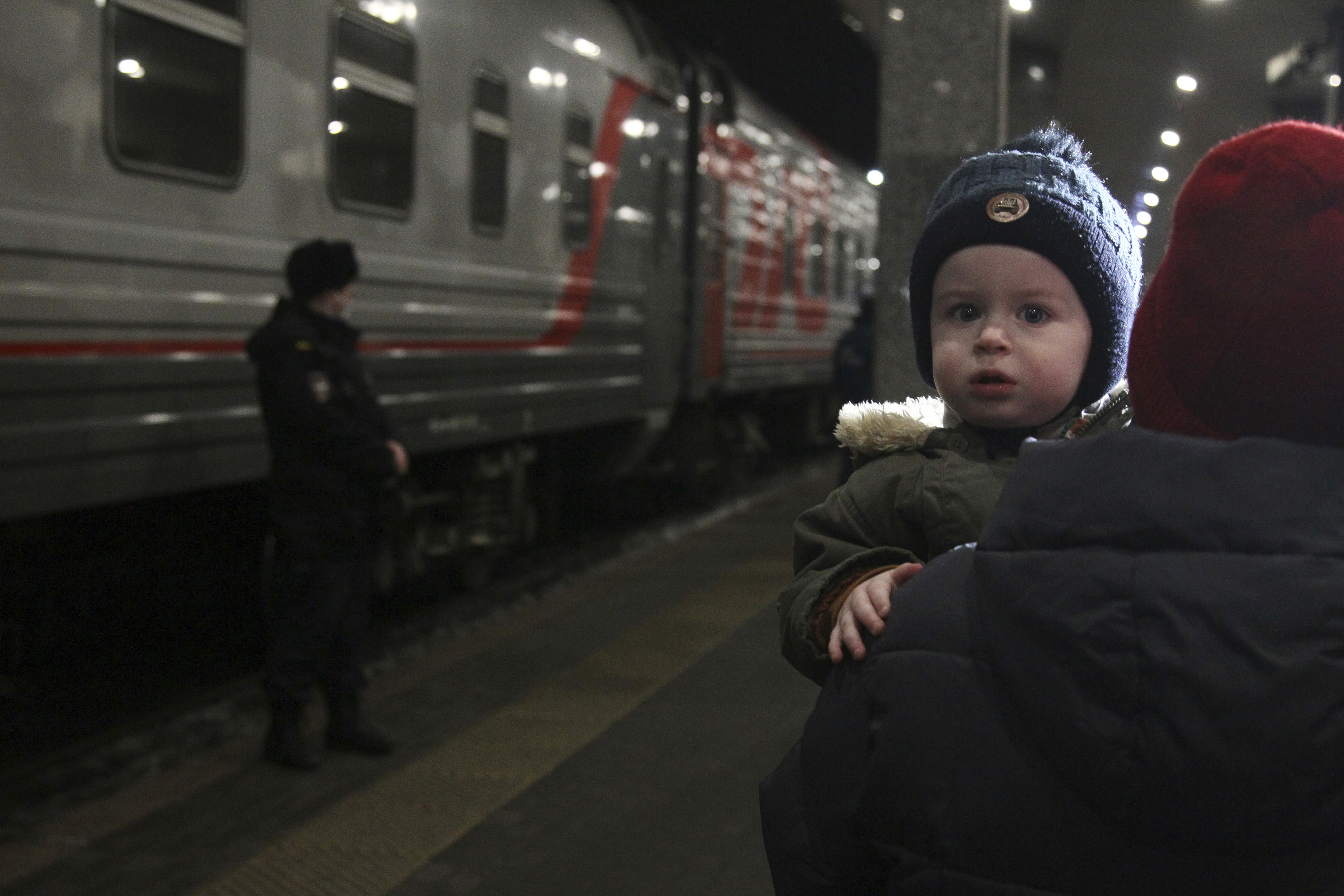 Una mujer lleva a un niño mientras son evacuados de la región de Donetsk.