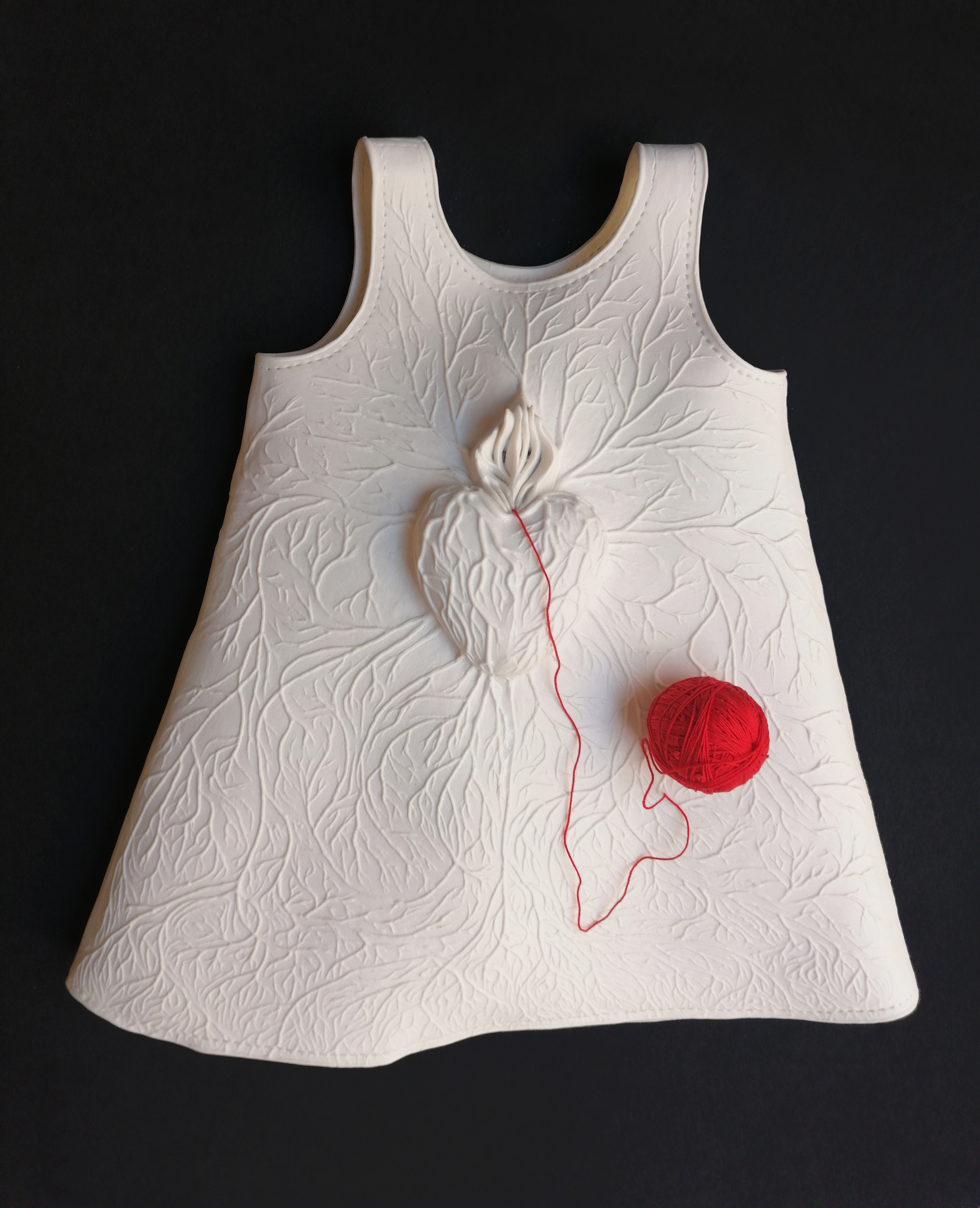 A NOS ENFANTS (A NUESTROS HIJOS) Porcelana de papel, modelada, engobada y estampada. Coccin a alta temperatura. Carrete de hilo, rojo. 36 cm x 37 cm x 7 cm de grosor. Ao 2019-2021.
