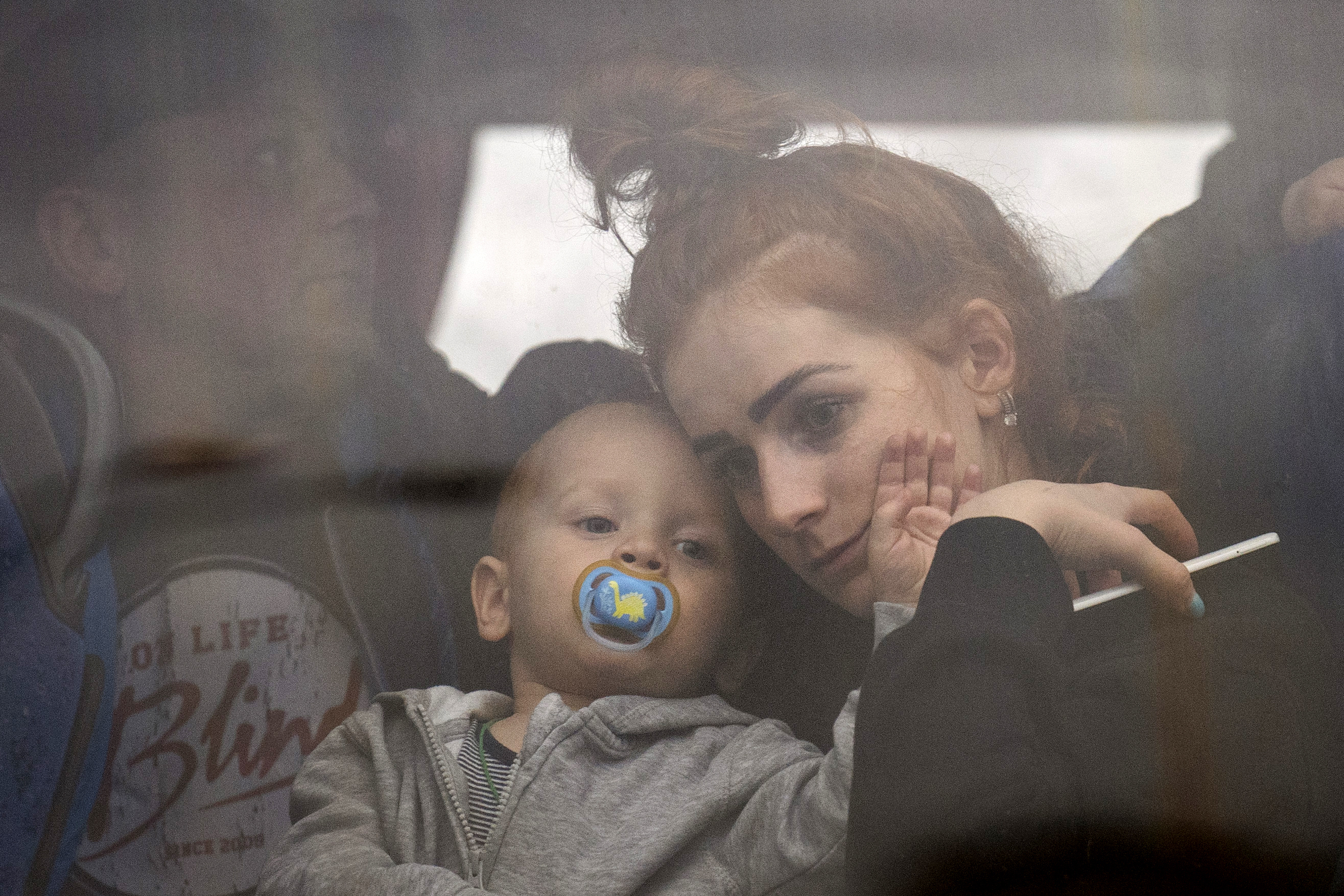 Una mujer y su hijo abandonan Kiev en autobs .