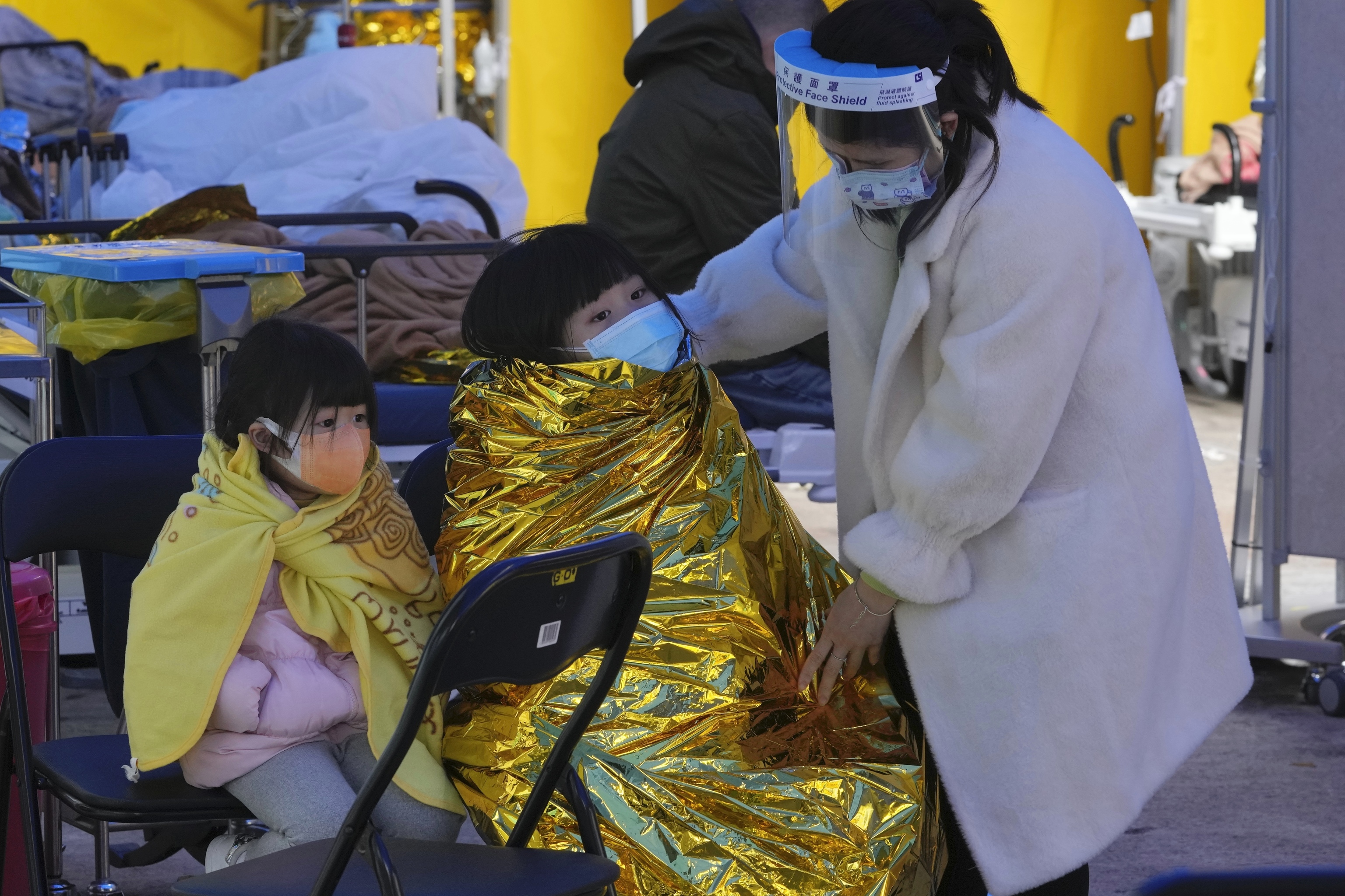 Una mujer con nios con mascarillas espera en un rea de tratamiento temporal improvisada fuera del Centro Mdico Caritas en Hong Kong, el viernes 18 de febrero de 2022.