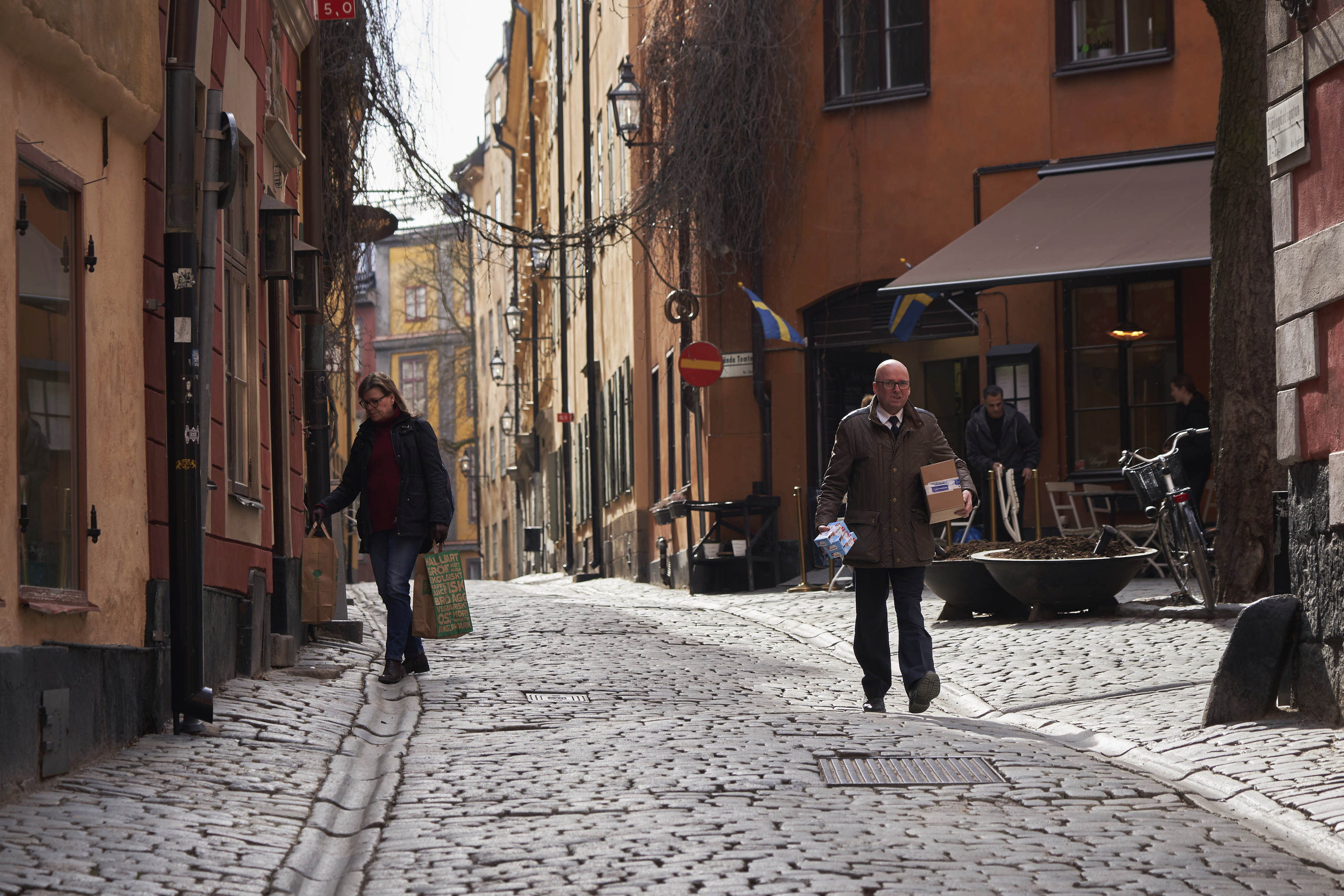Varias personas caminan por una tranquila calle adoquinada en Estocolmo en marzo de 2020.