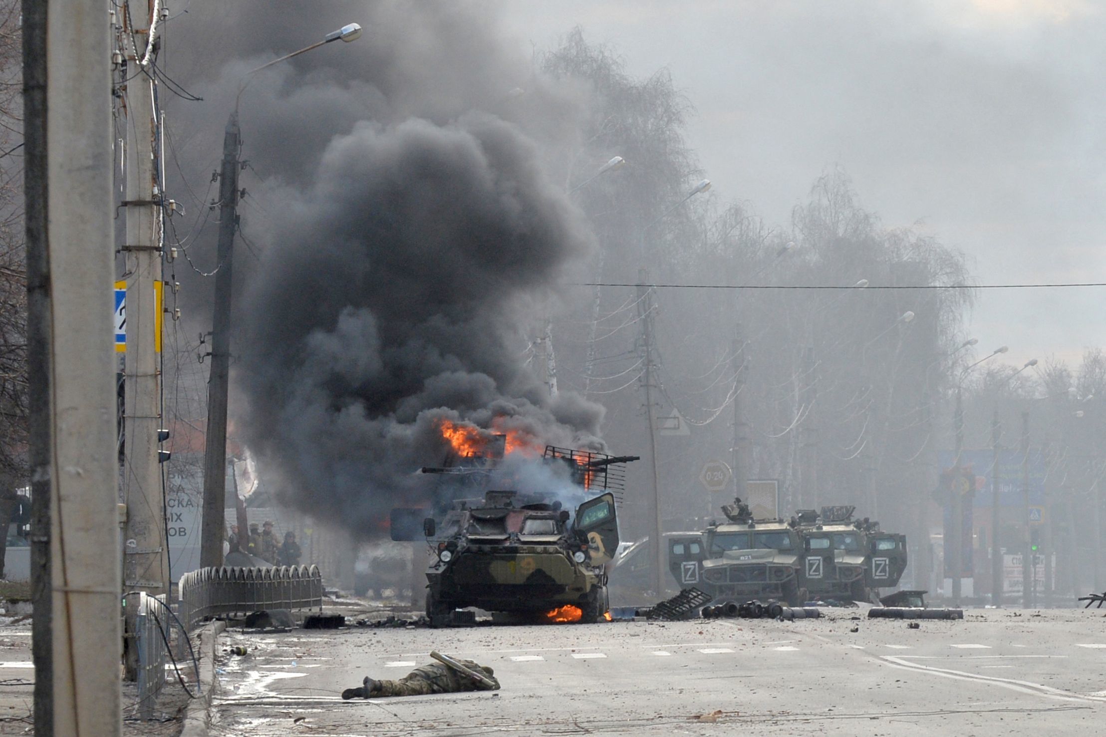 Un blindado ruso ardiendo junto al cuerpo de un soldado, en Jarkov.