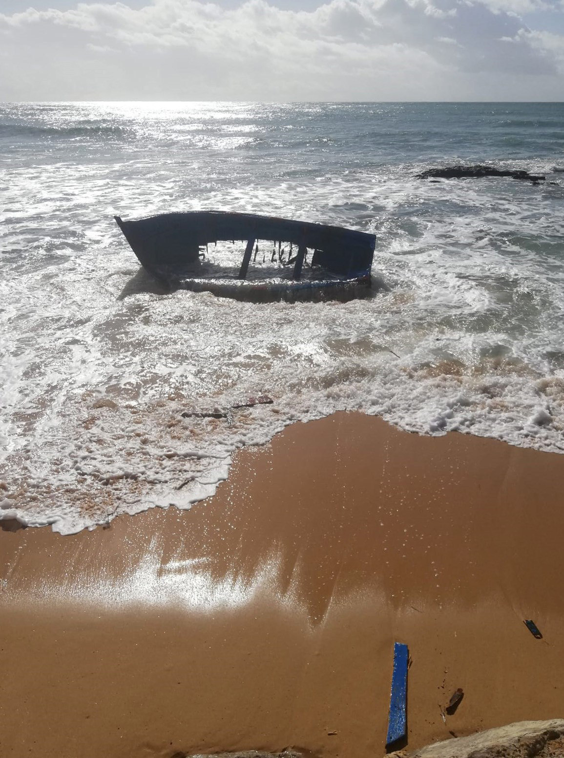 Los restos de una patera naufragada, varados en la orilla en la playa de Caños de Meca, en Cádiz.