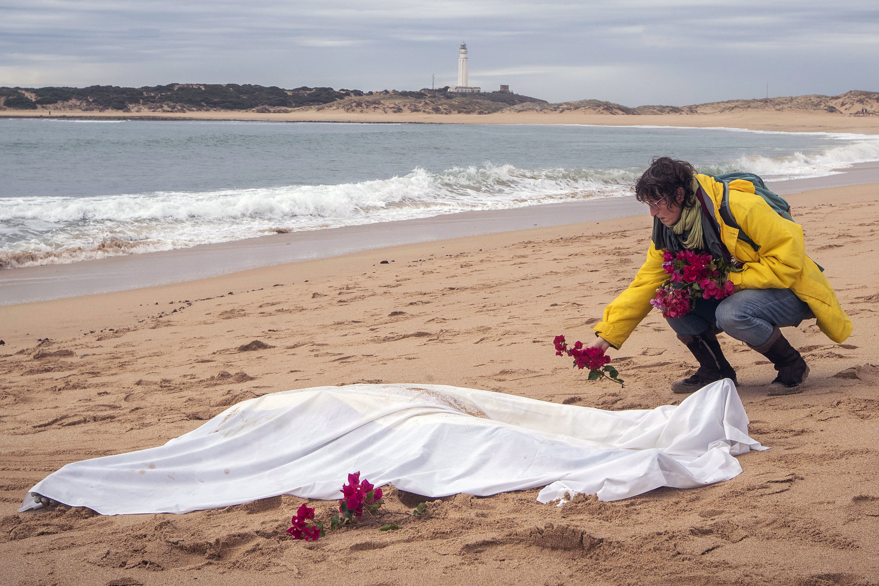 Una mujer deposita flores junto al cadáver de un inmigrante arrastrado por el agua.