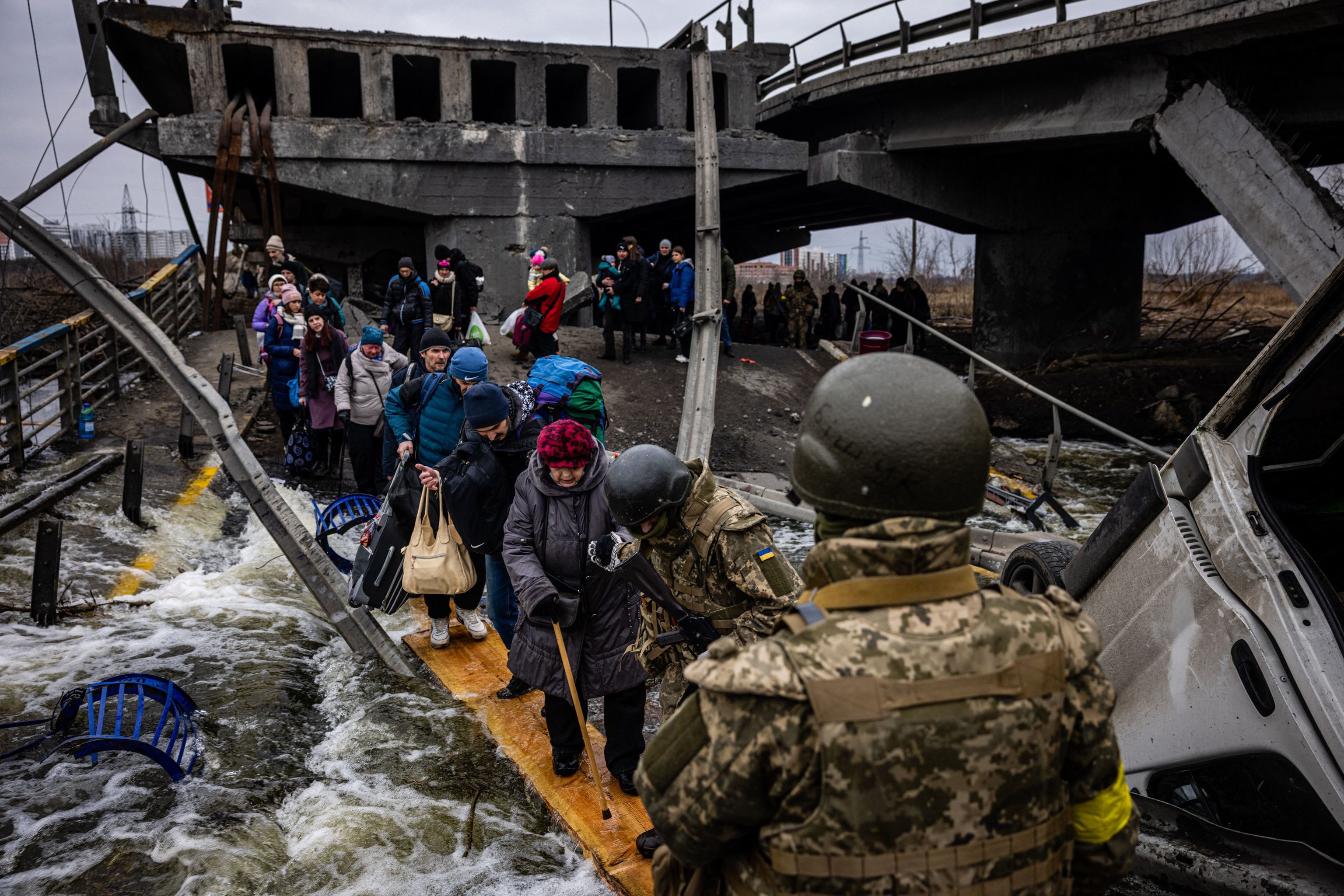 Civiles intentan huir de Irpin, Ucrania, atravesando el río por una tabla