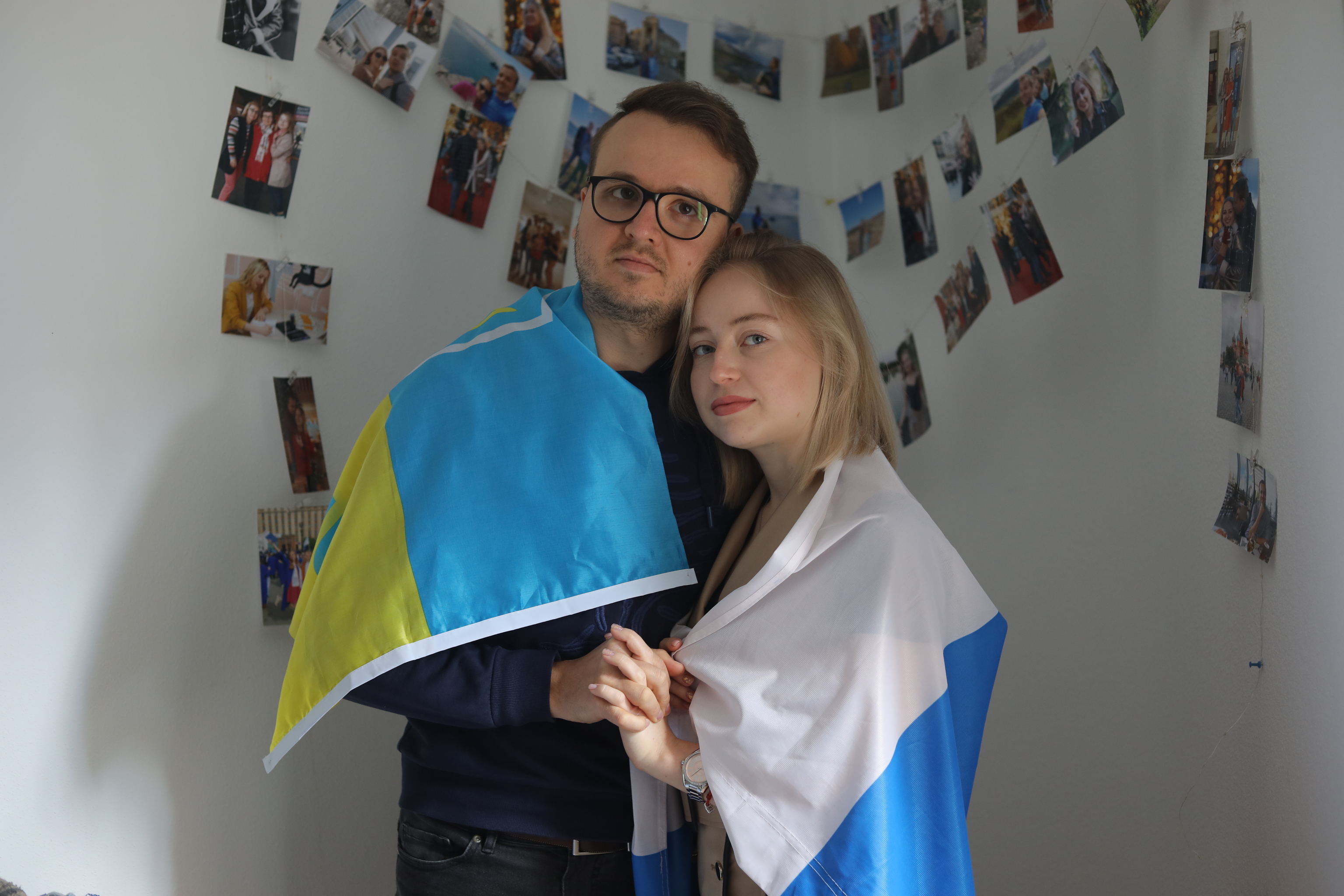 Andrey, con una bandera de Ucrania, y Eva, con una de Rusia, son pareja