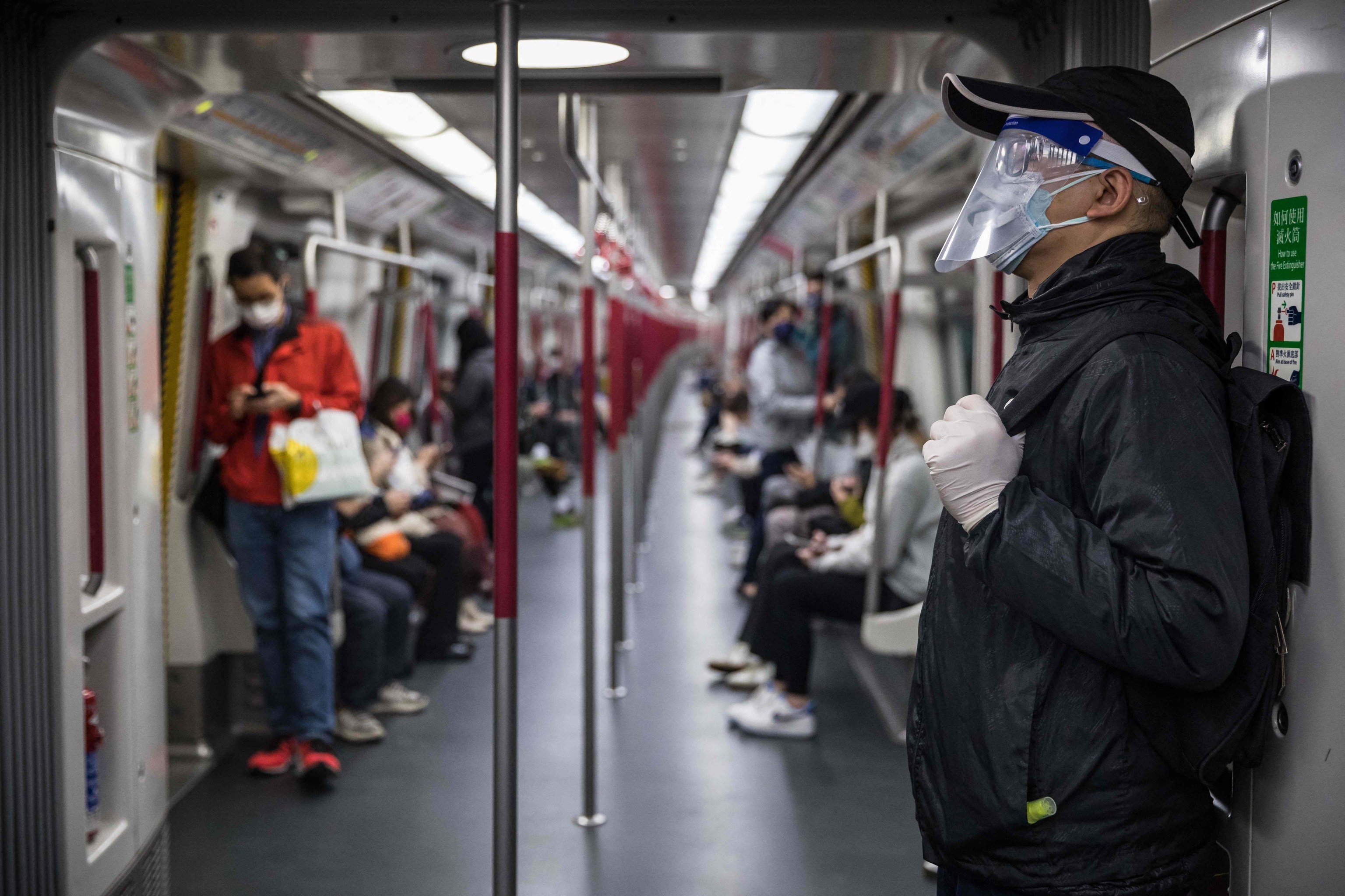 Un hombre con una careta y guantes viaja en tren en Hong Kong el 8 de marzo de 2022, en medio del peor brote de coronavirus Covid-19 de la historia de la ciudad.