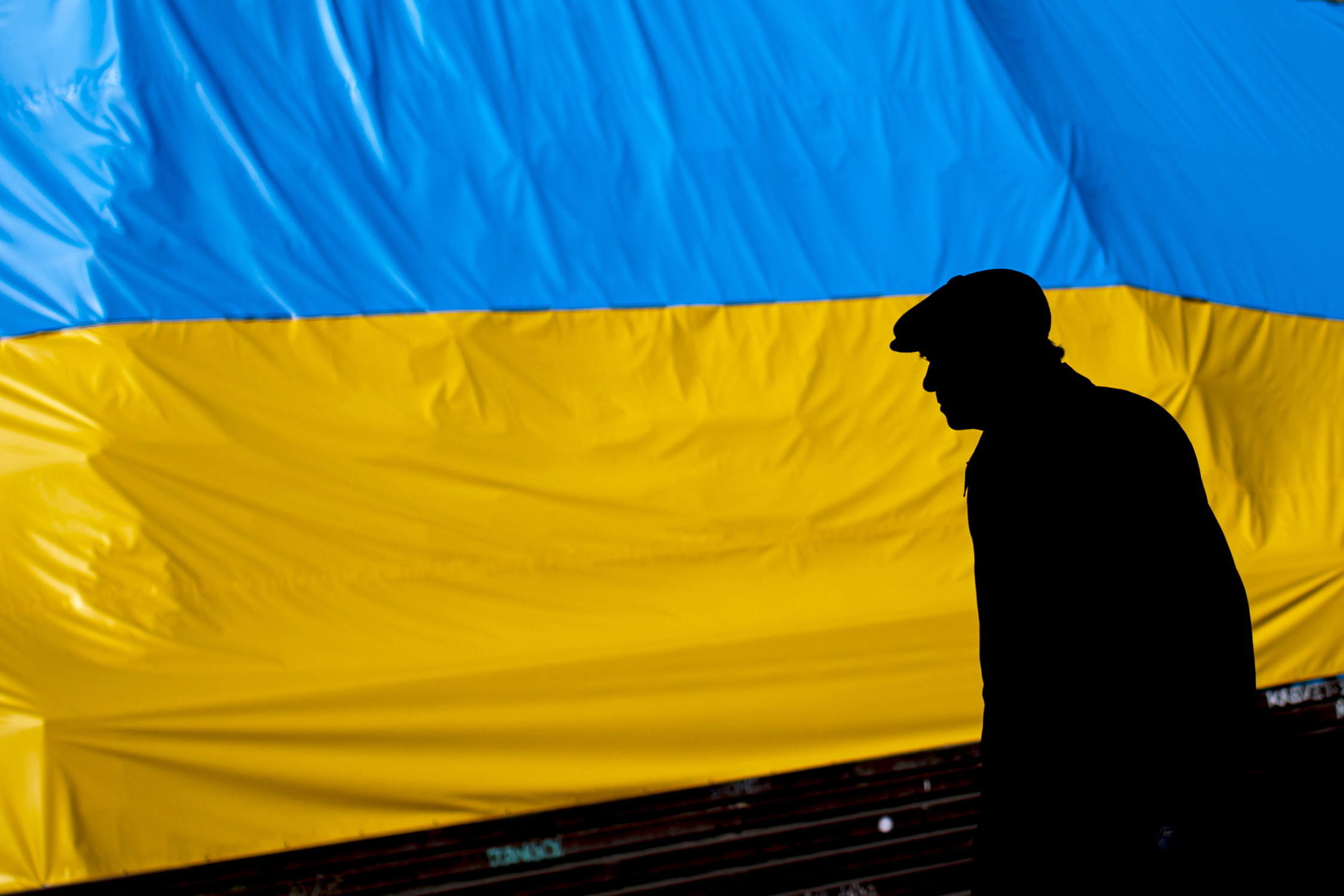 Un hombre camina frente a una bandera de Ucrania