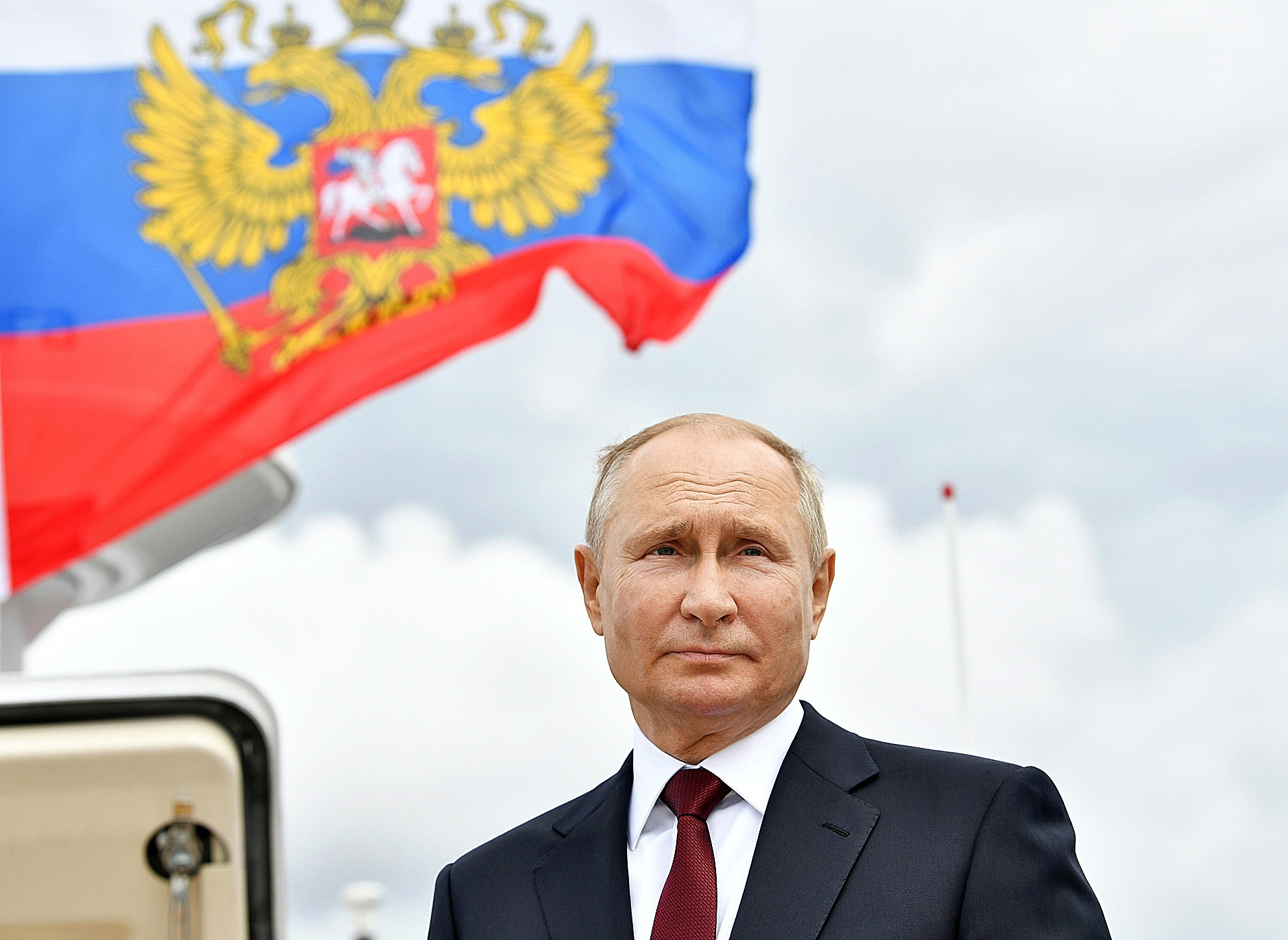 Putin delante de una bandera rusa con el guila bicfala